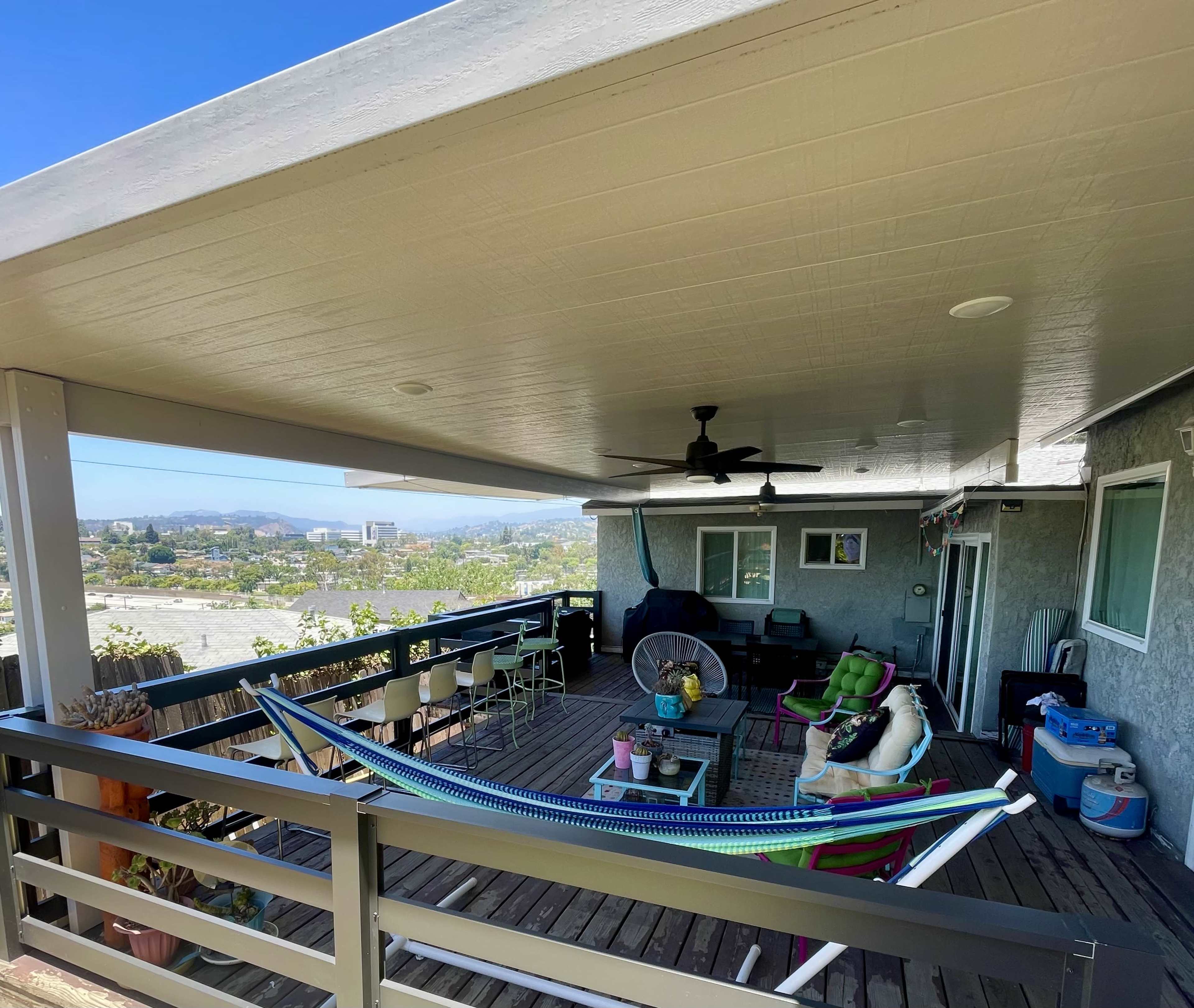 A covered patio features a hammock and seating area overlooking a scenic view.