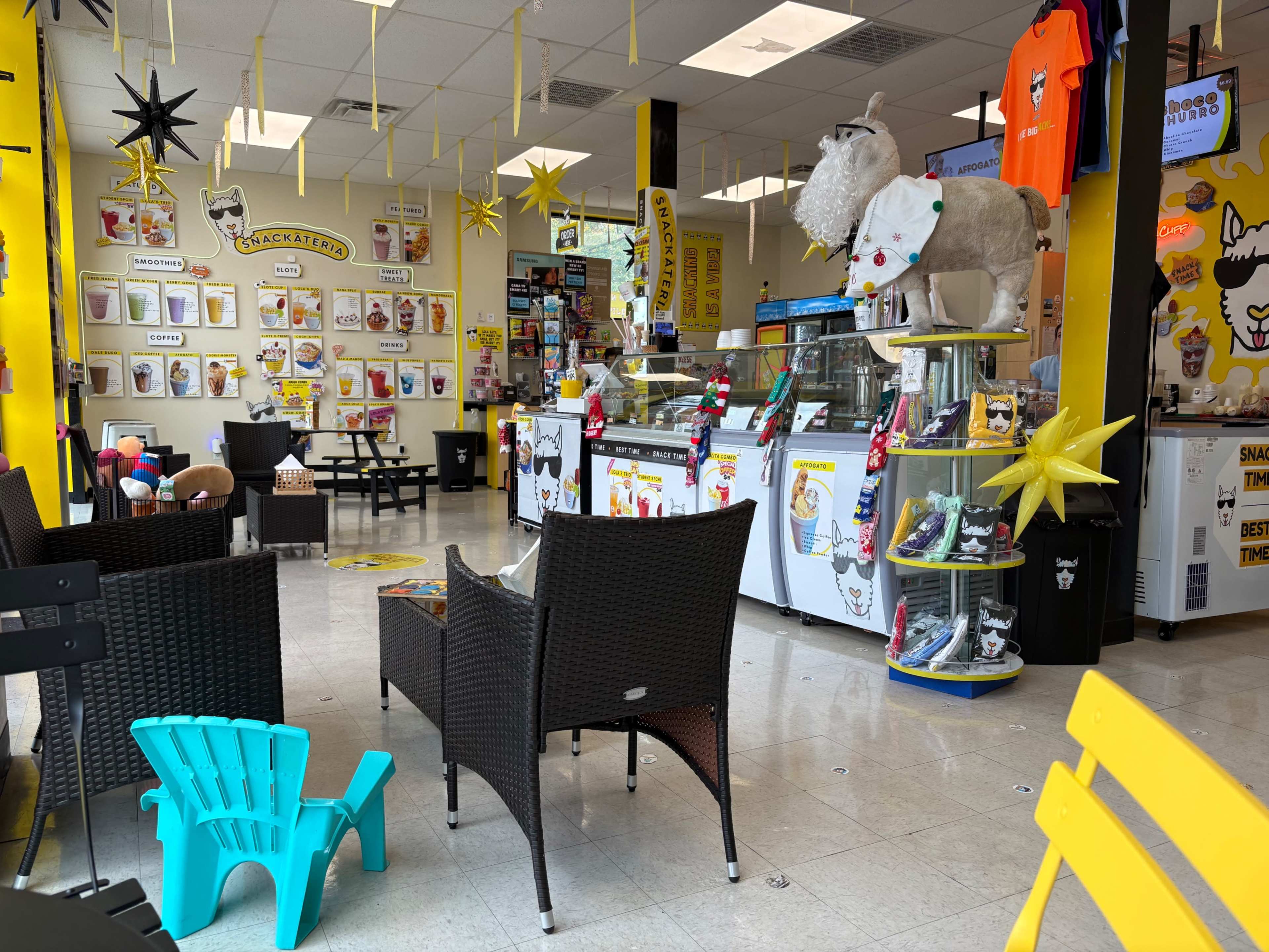 The interior of a colorful ice cream shop features a glass display case with ice cream, yellow and black decor, and a variety of seating options.