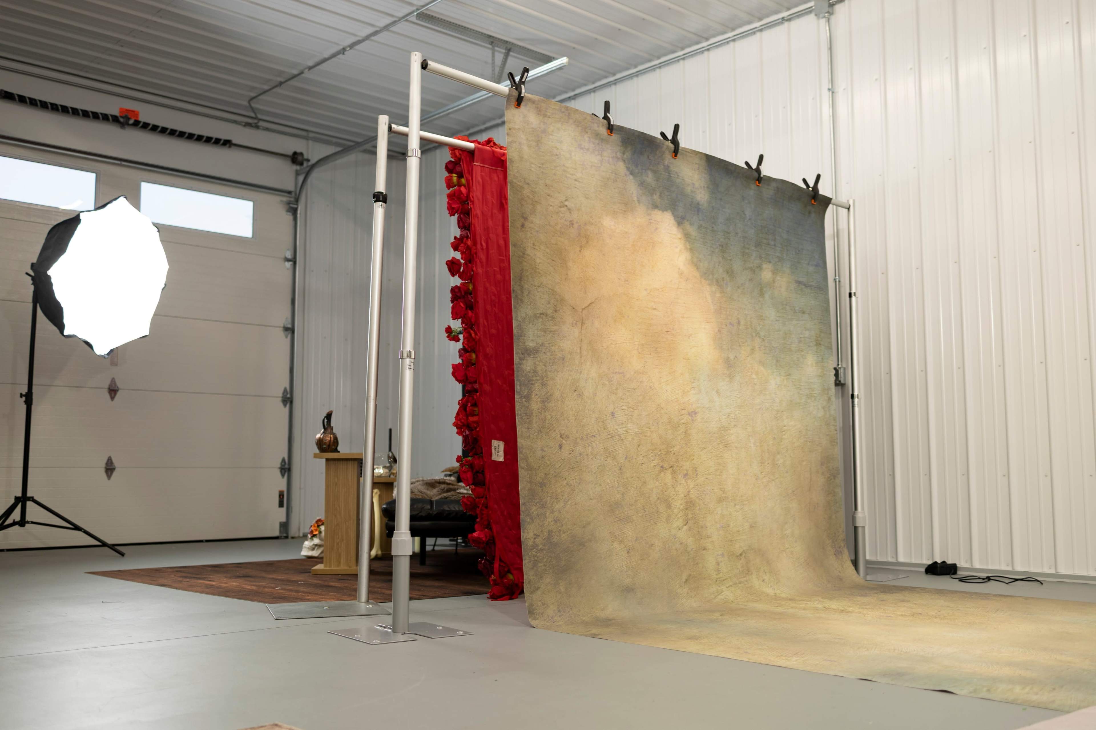 The image shows a photography studio setup with a backdrop on a stand, a decorative red fabric draped alongside it, and a softbox light positioned on the left.