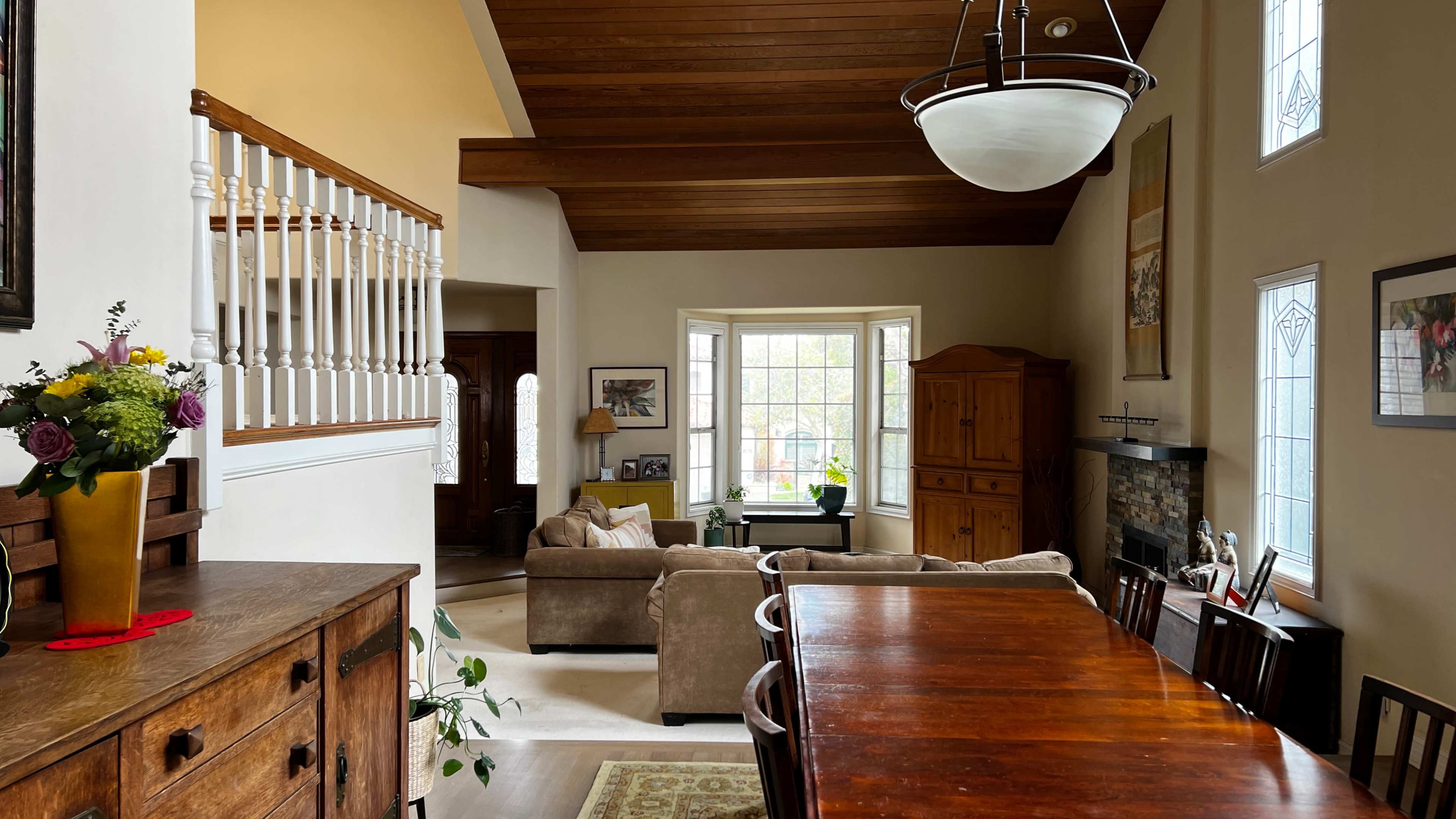 A spacious living area with a dining table, a couch, and large windows allowing natural light to enter.