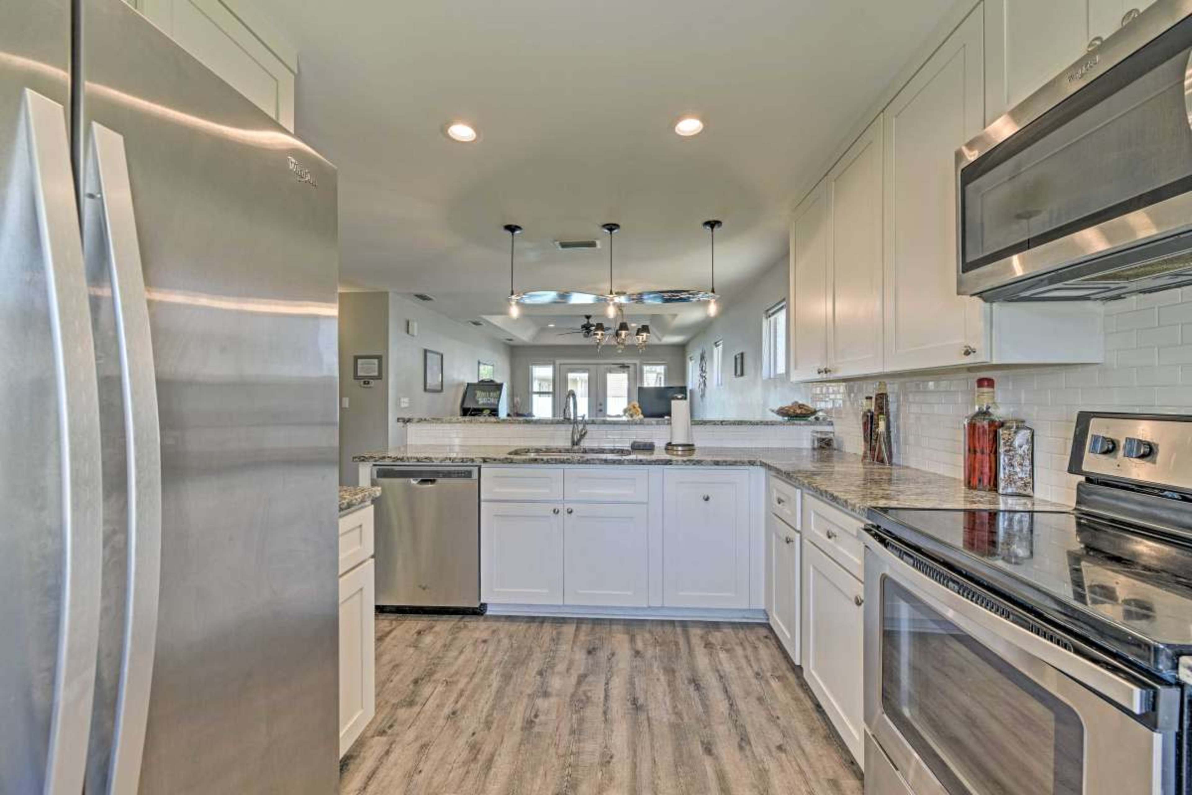 A modern kitchen with stainless steel appliances, white cabinets, and a granite countertop.