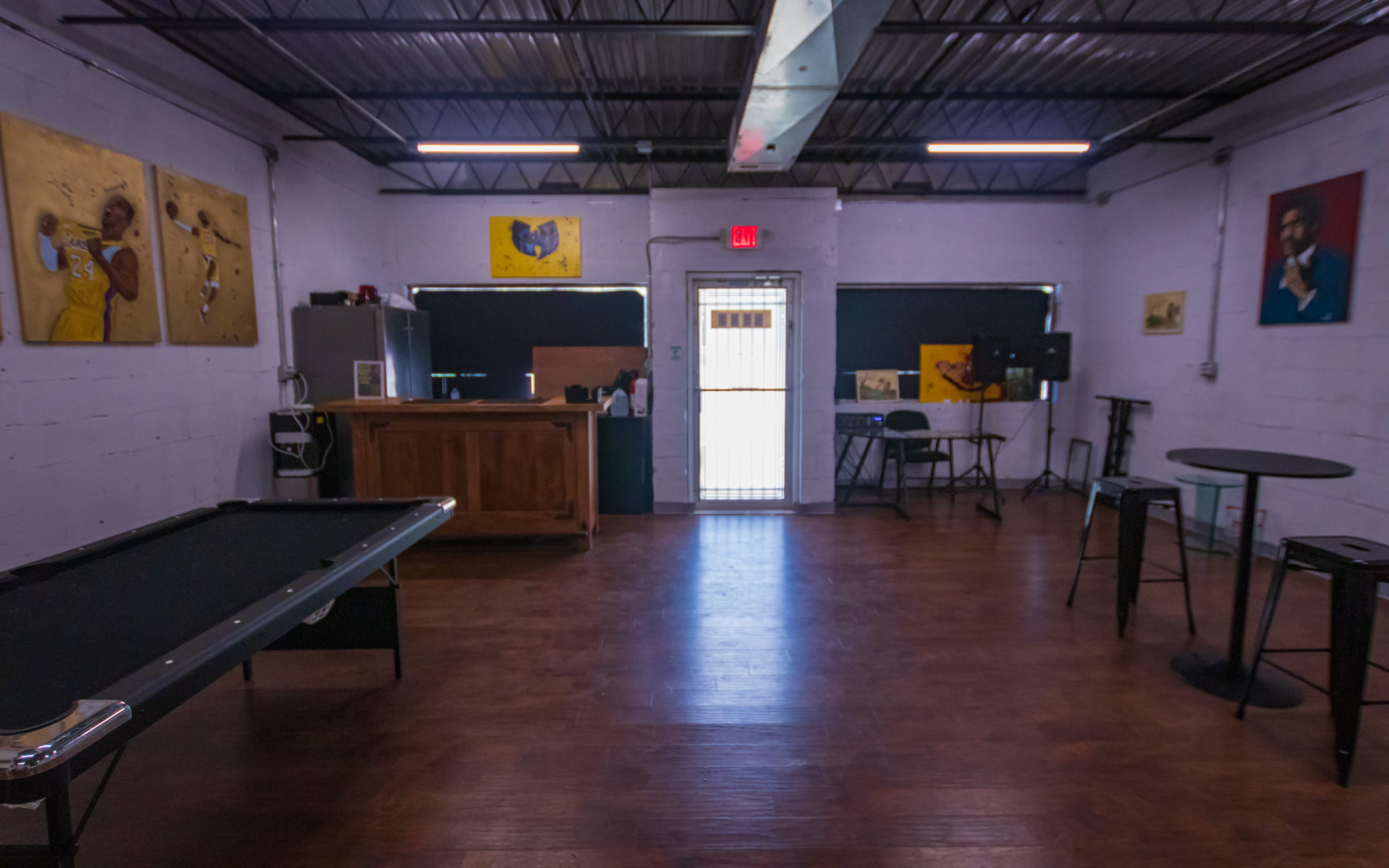 An interior room featuring a pool table, a wooden bar, and several pieces of artwork on the walls.