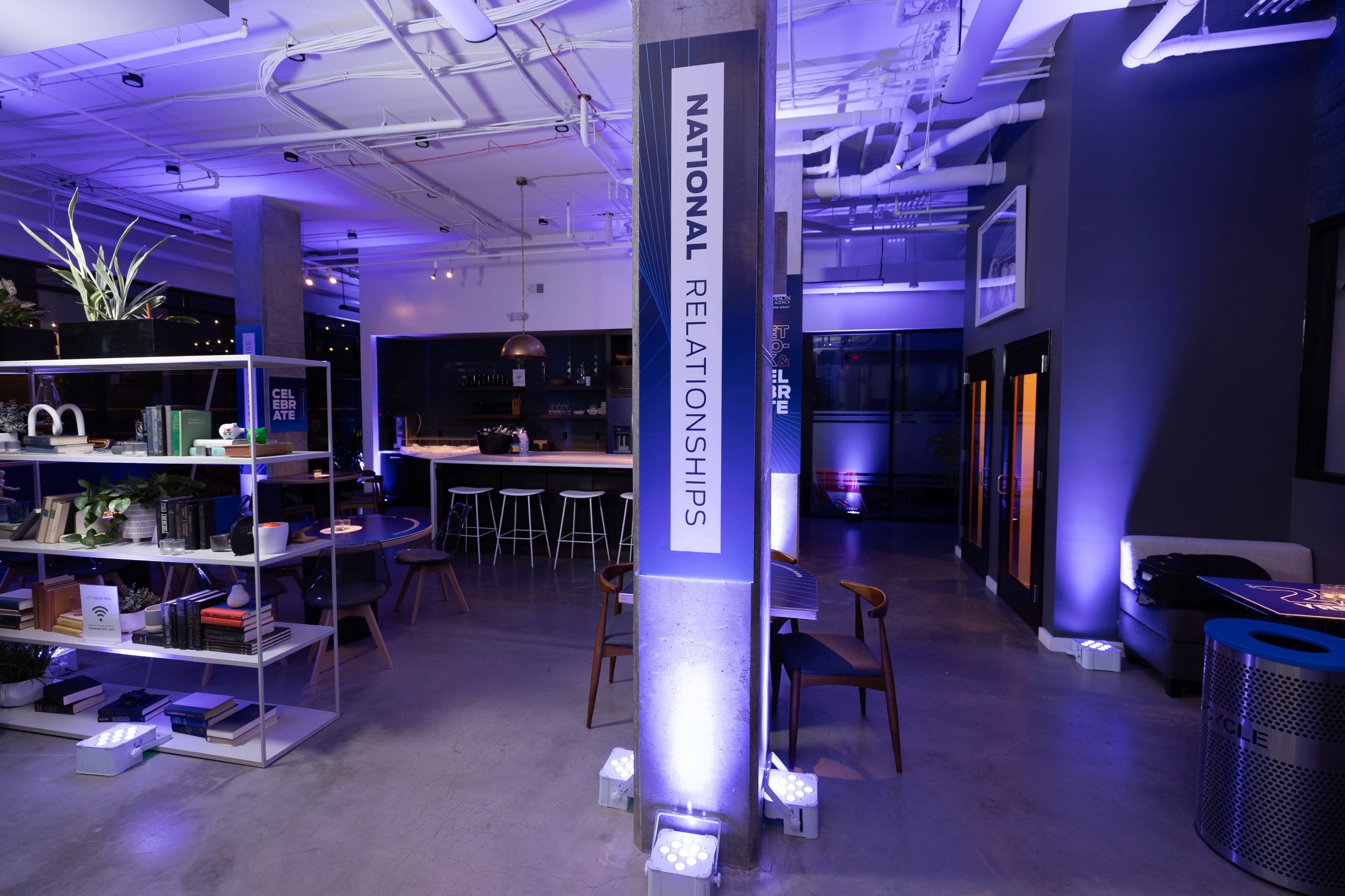 A modern interior space with a large sign reading "NATIONAL RELATIONSHIPS" on a pillar, surrounded by stylish furniture and ambient lighting.