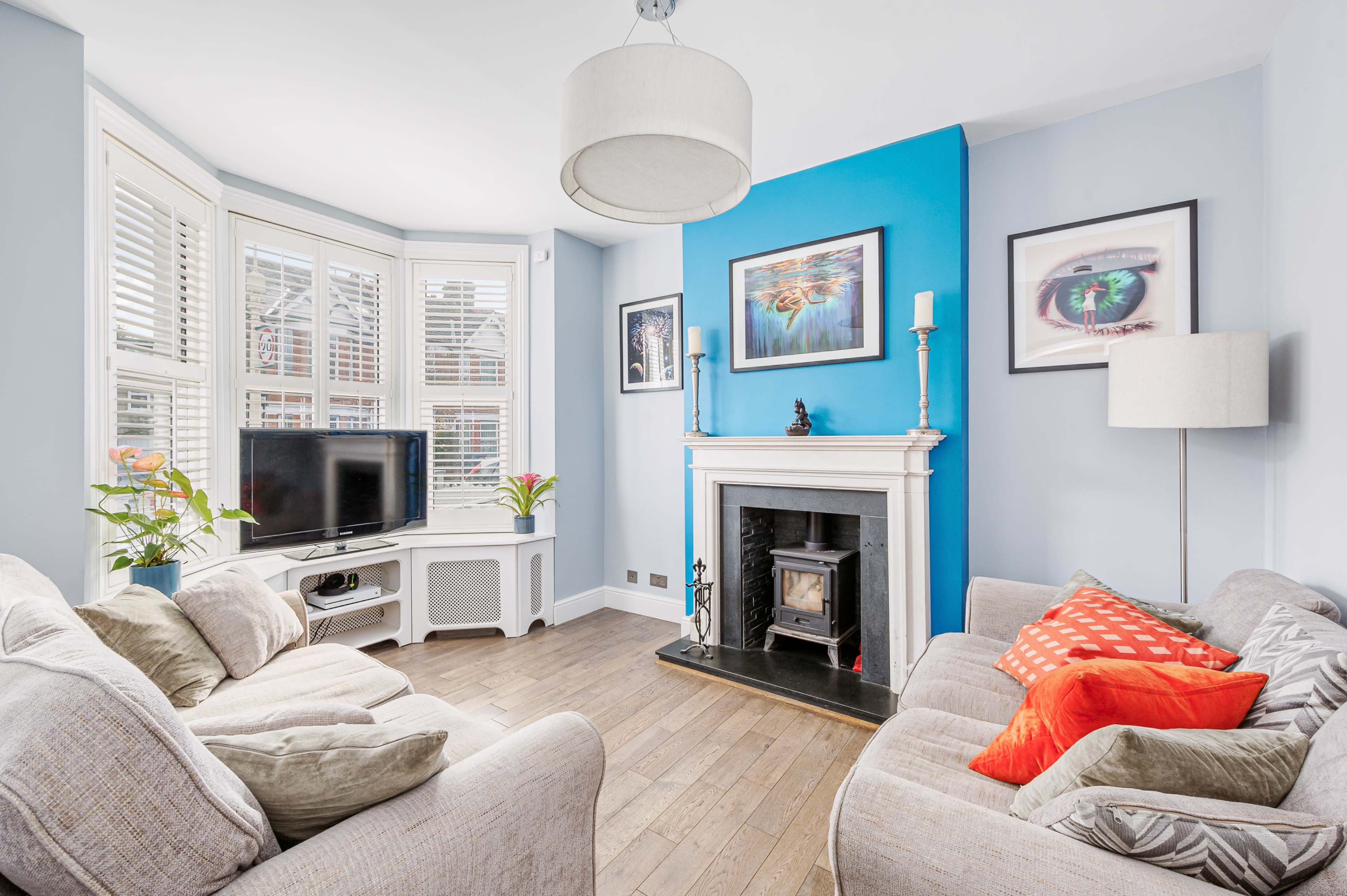 The living room features a bay window with a television and a fireplace, surrounded by light blue walls and comfortable seating.