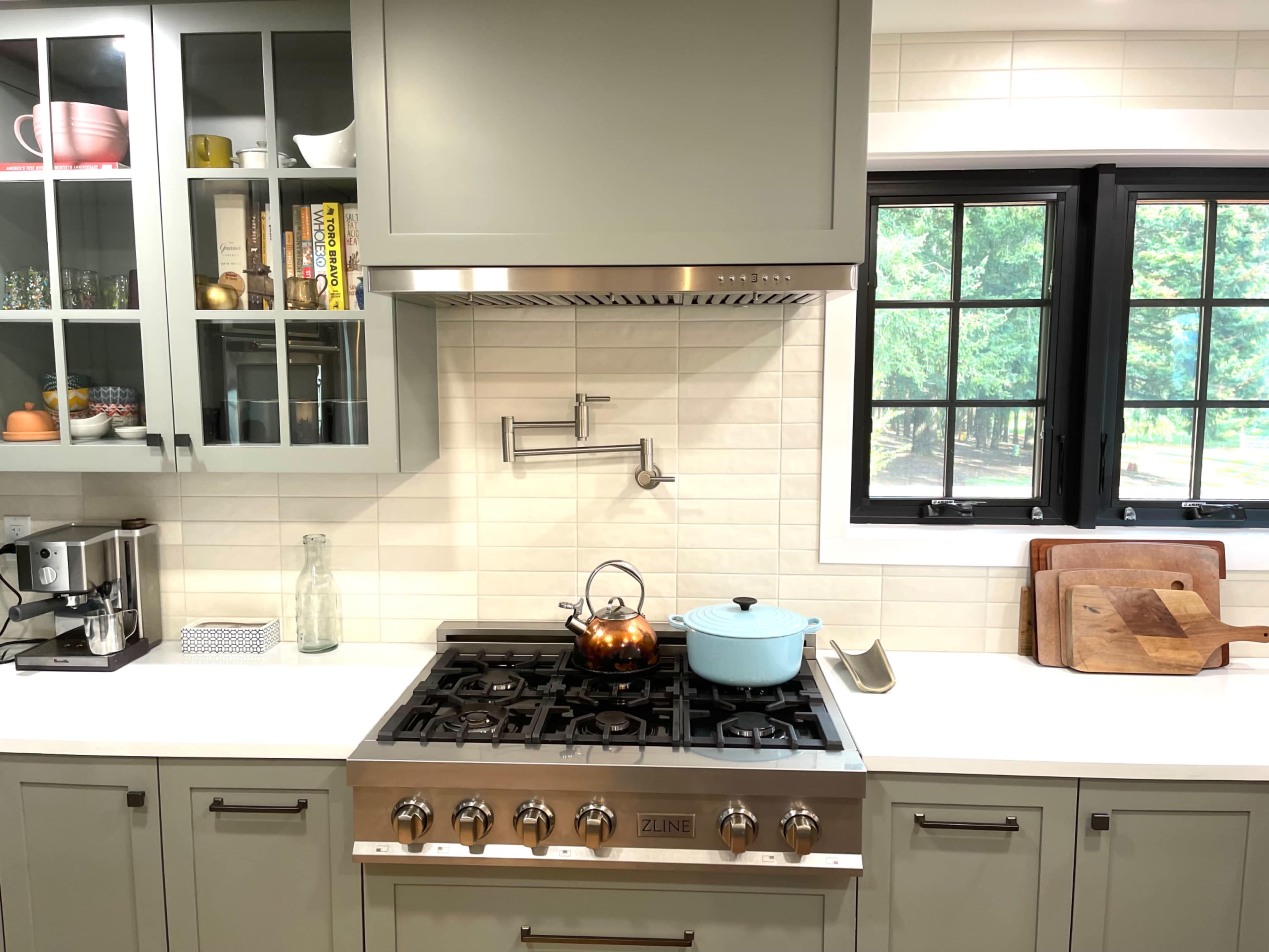 A modern kitchen with a gas stove, a kettle on the burner, and organized cabinets showcasing cookware.