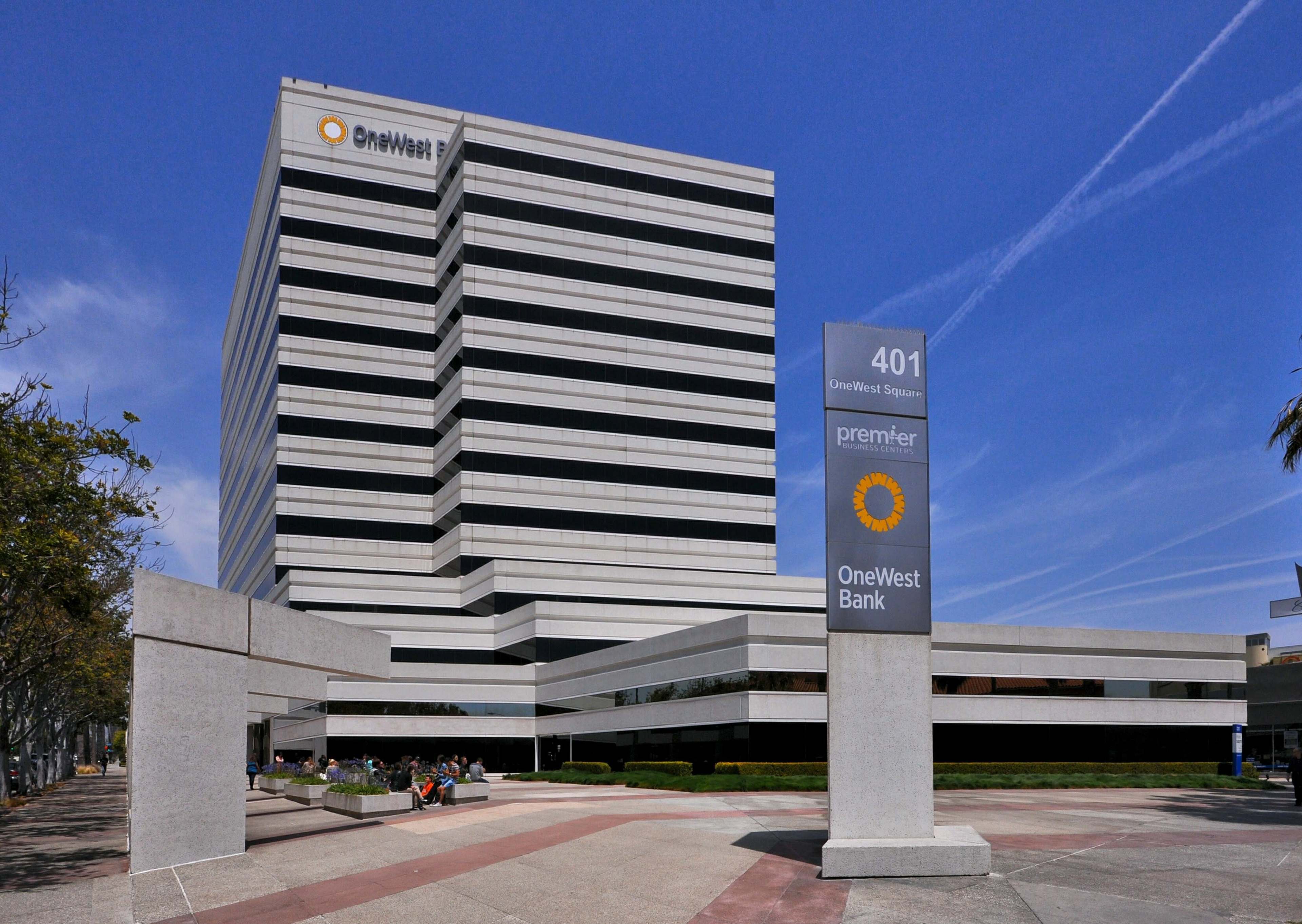 A modern, multi-story commercial building with a prominent sign for OneWest Bank and nearby signage indicating its address and a business called premier.