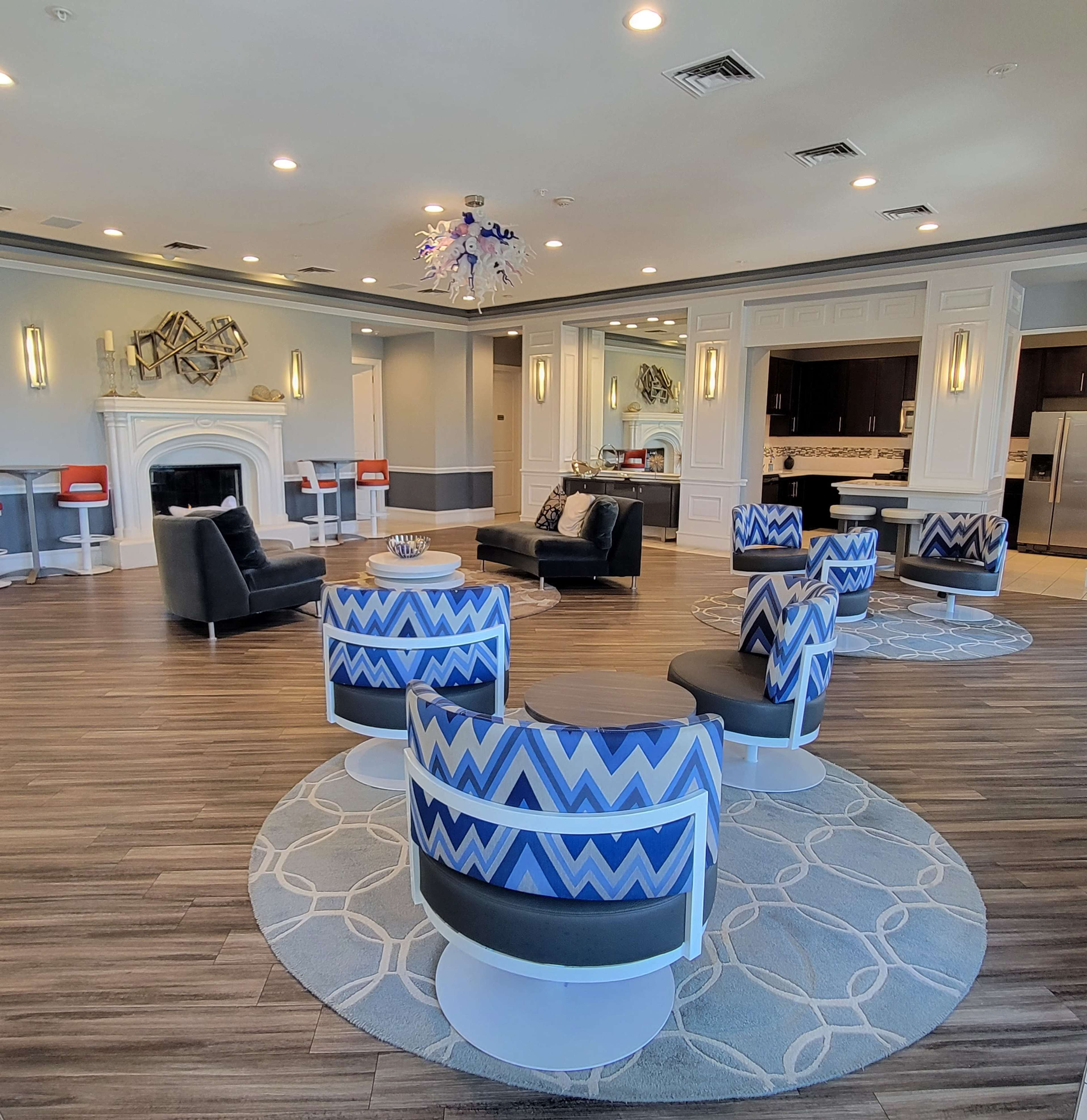 The image shows a modern lounge area with circular seating, a fireplace, and a contemporary chandelier.