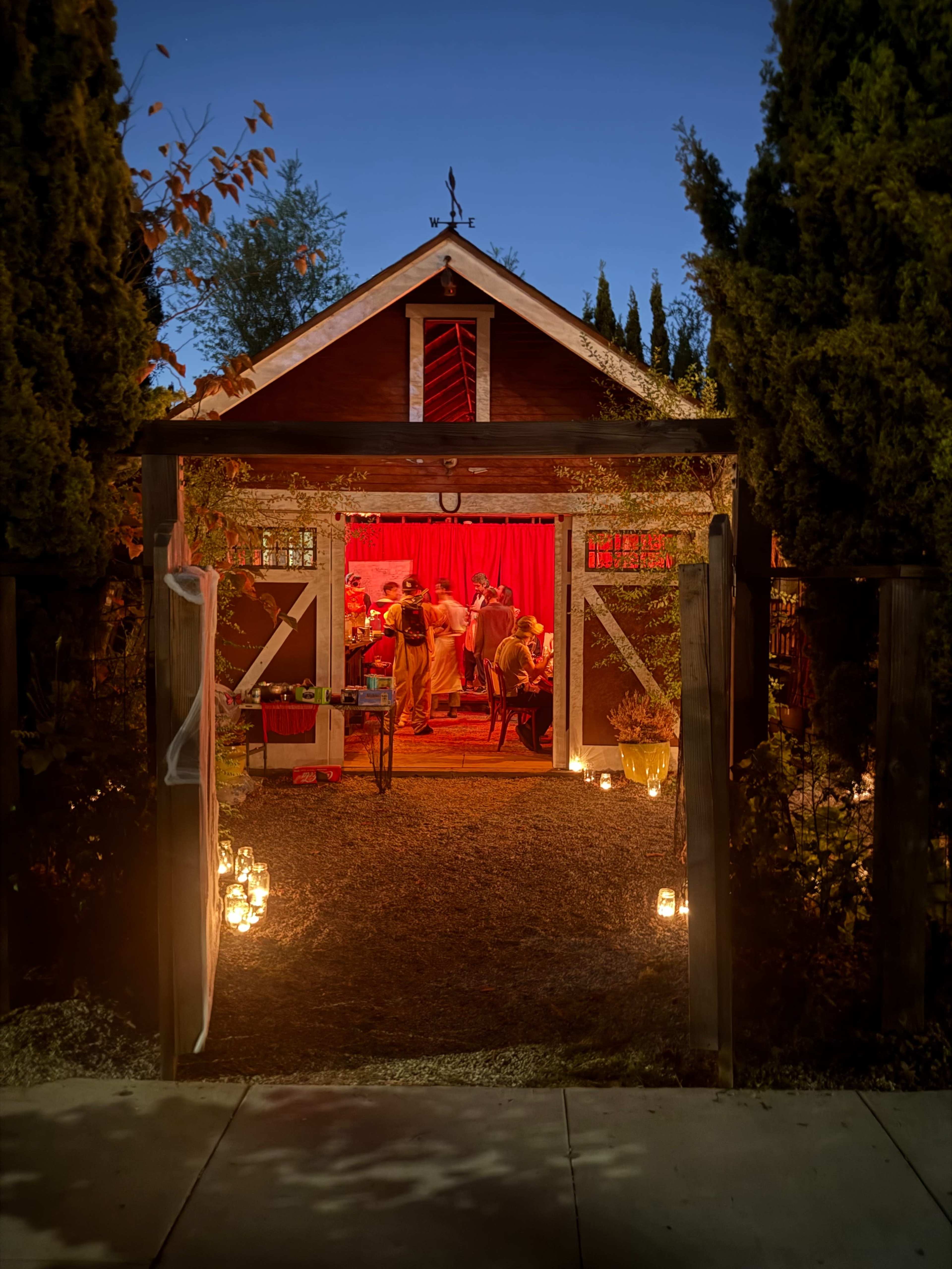 A decorated barn with warm lighting and people gathered inside creates an inviting atmosphere in the evening.
