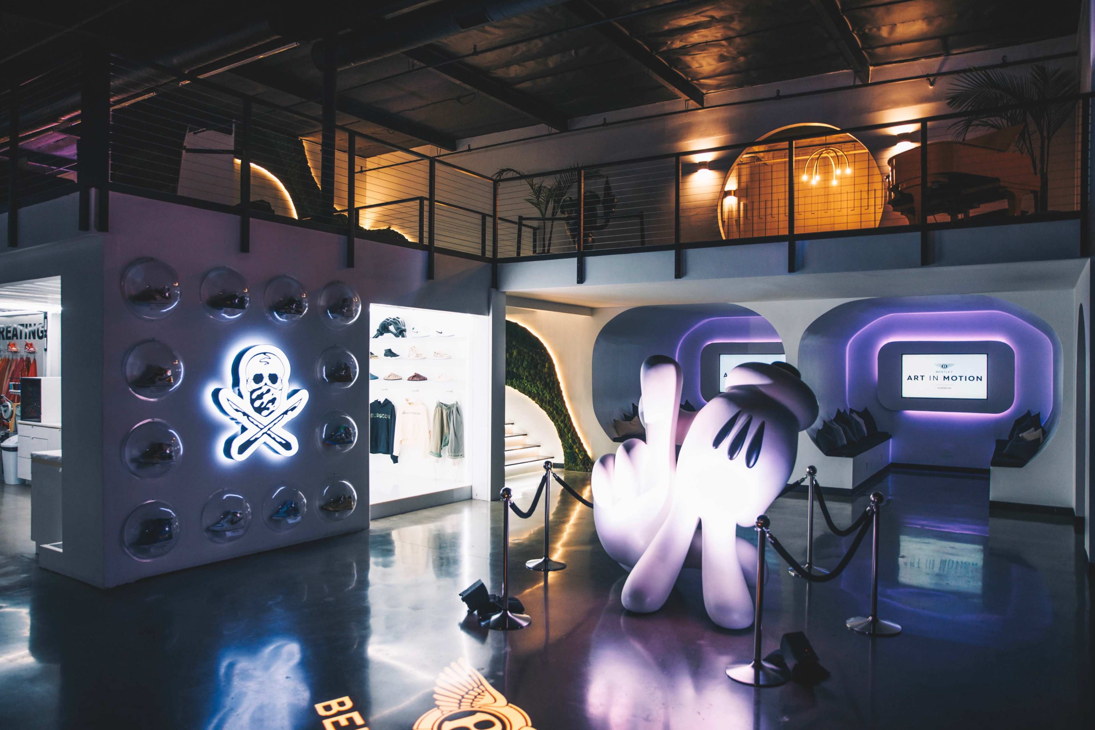 A modern indoor space featuring stylized artwork, display sections, and a staircase leading to an upper level.