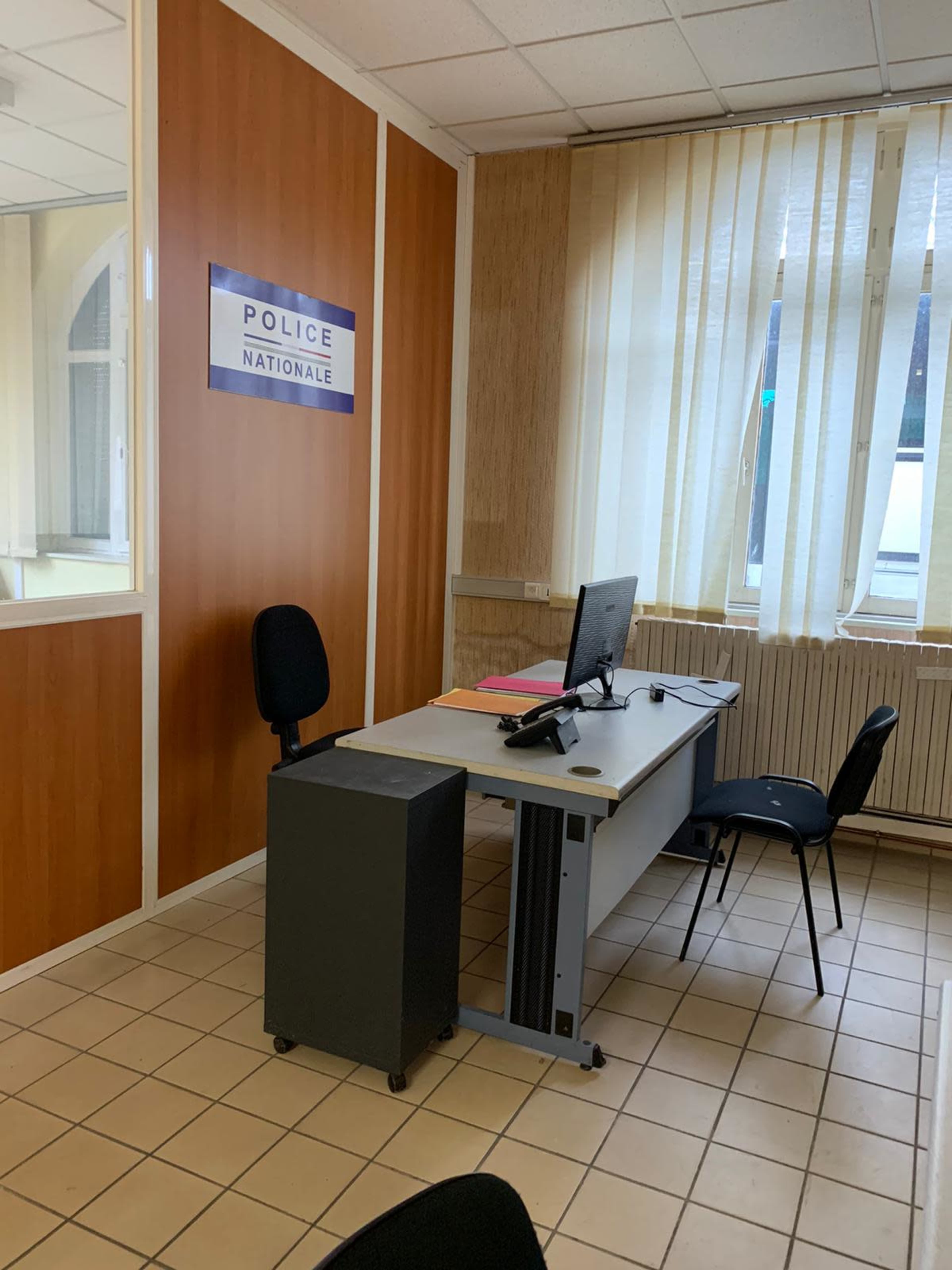 A police station office features a desk with a computer, chair, and a wall sign reading "POLICE NATIONALE."