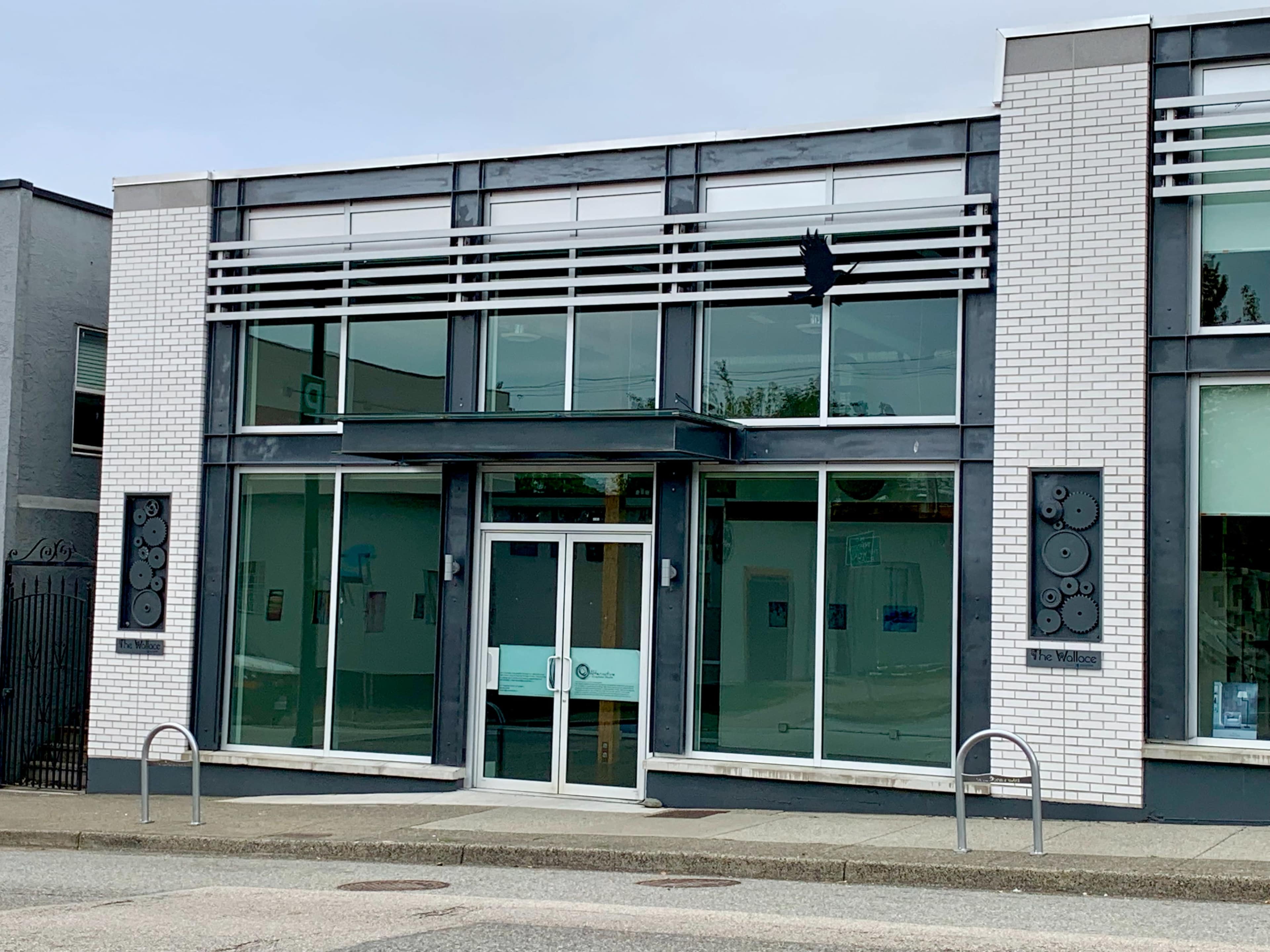 A modern building with large glass windows and a minimalist entrance, featuring circular designs on the side walls.