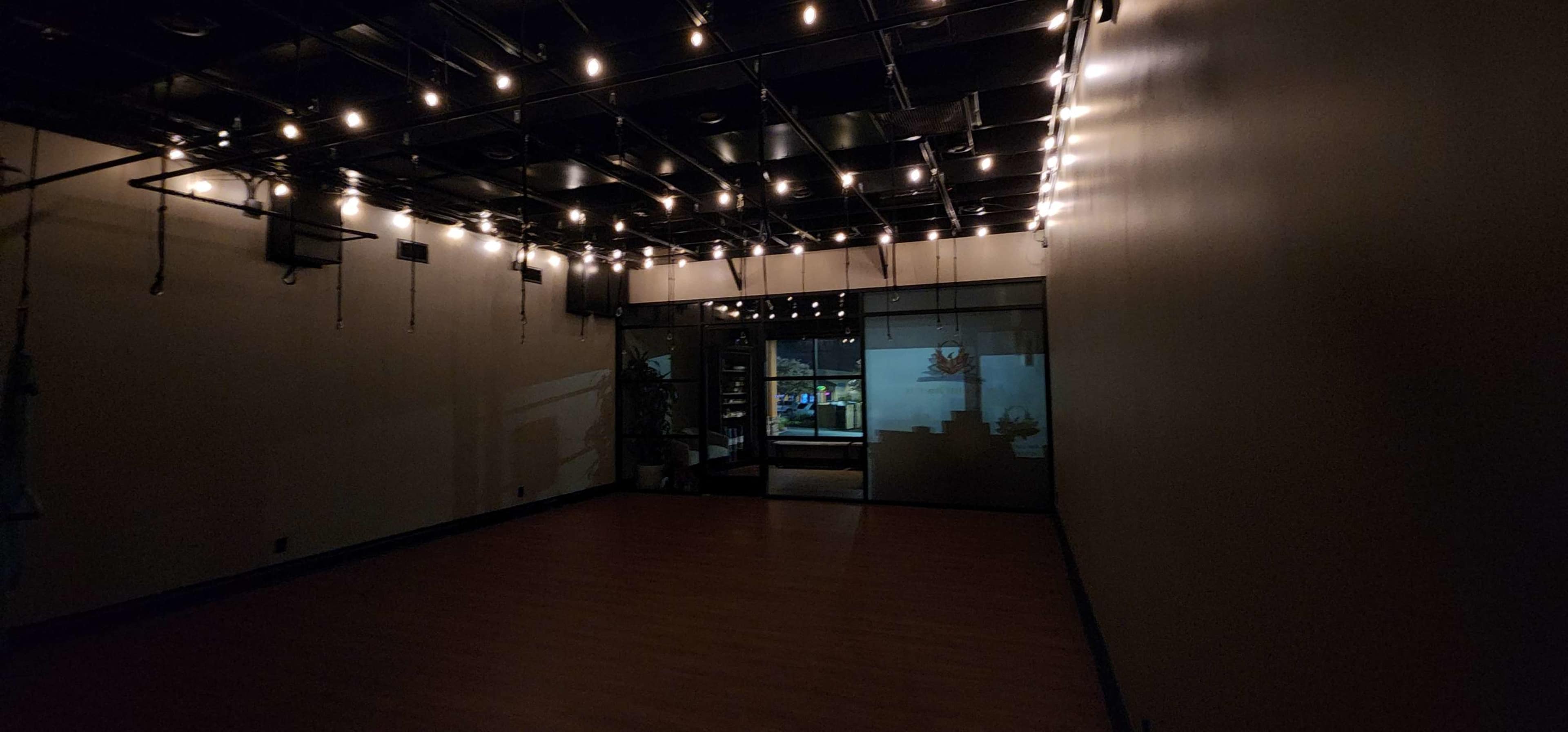 A dimly lit interior space with string lights on the ceiling and a large glass door leading to another area.