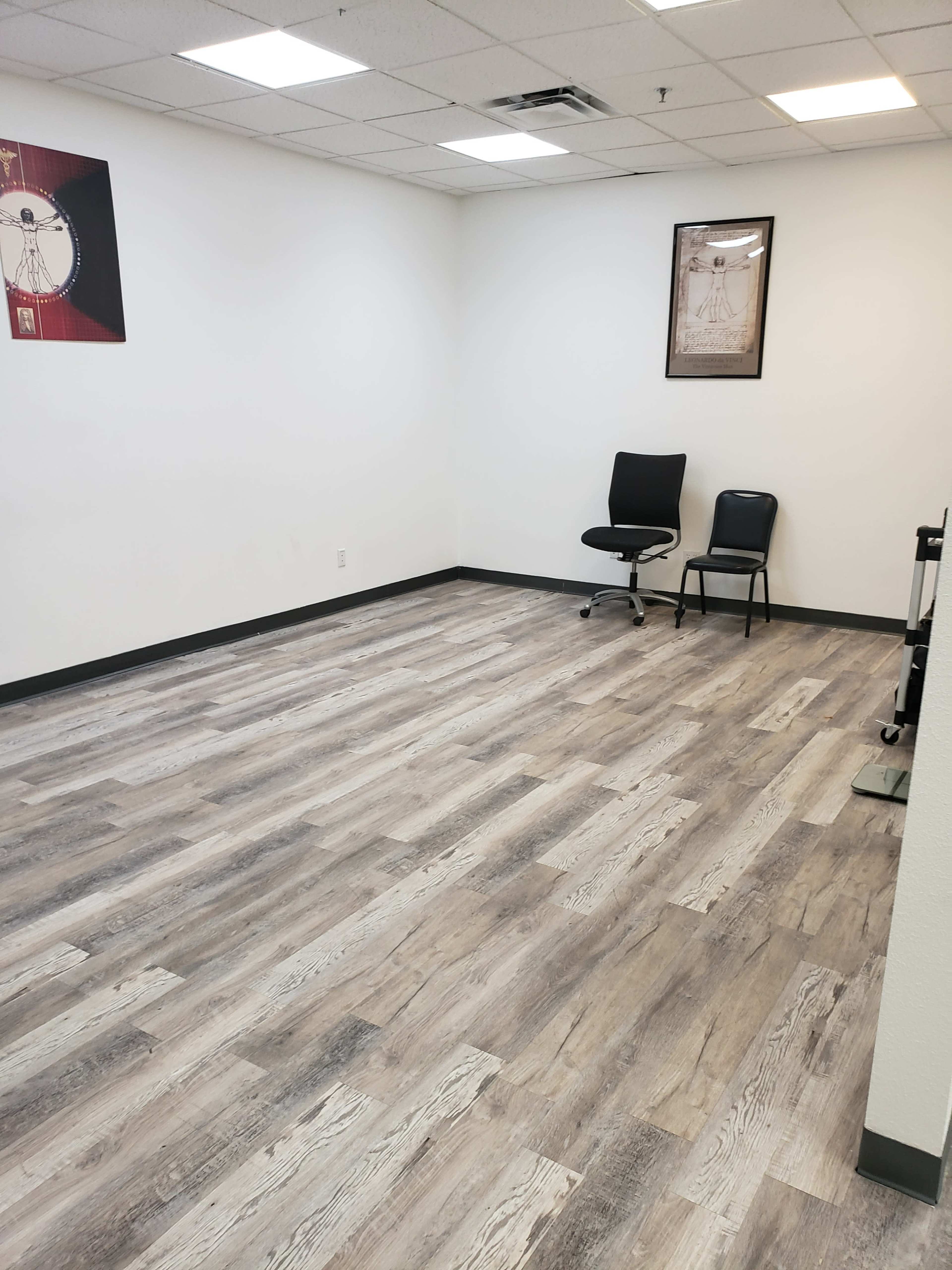 A sparsely furnished room with two black chairs and a light-colored wooden floor.