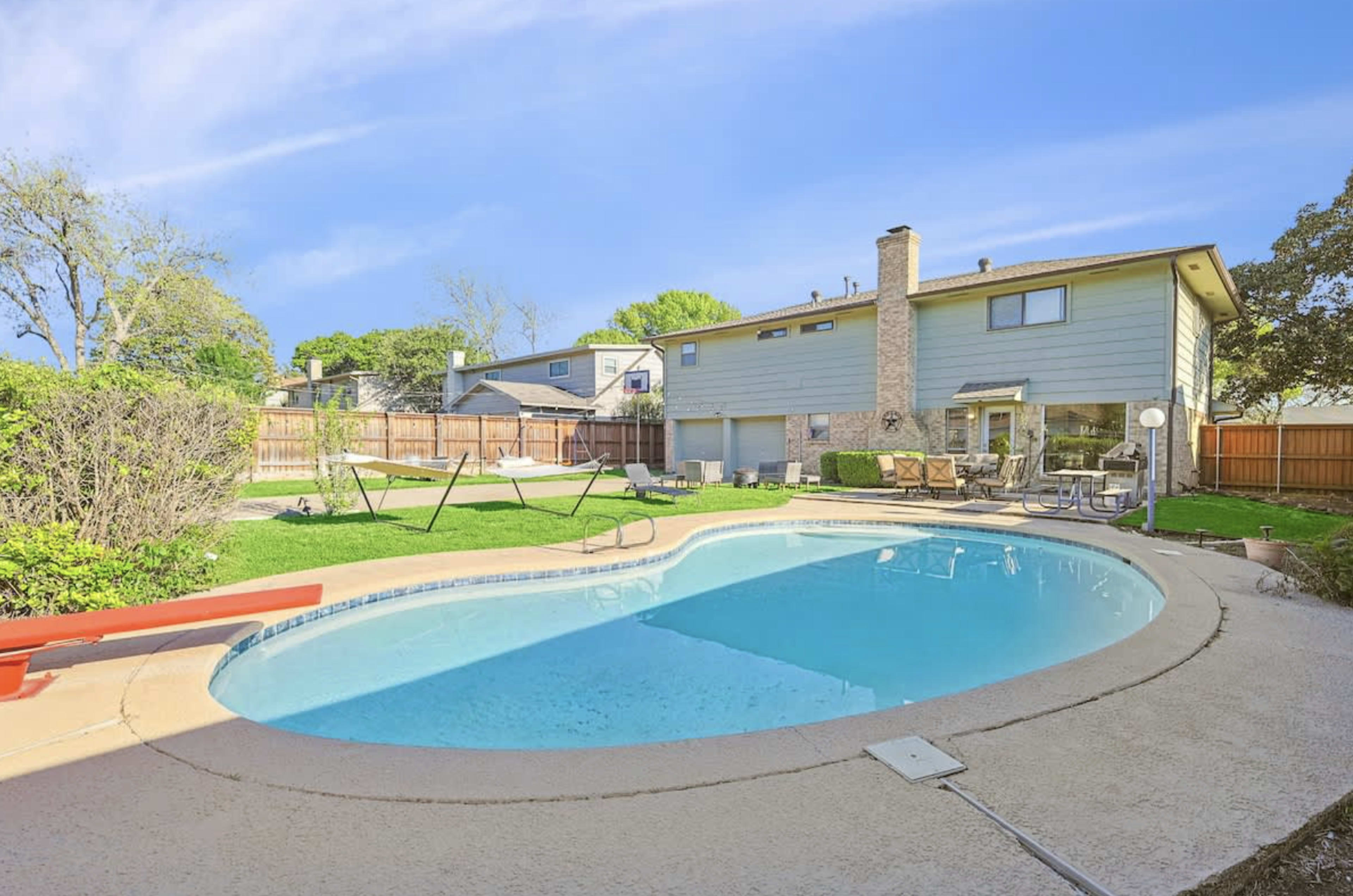 The image shows a backyard with a swimming pool, a swing set, and a two-story house with a stone chimney.
