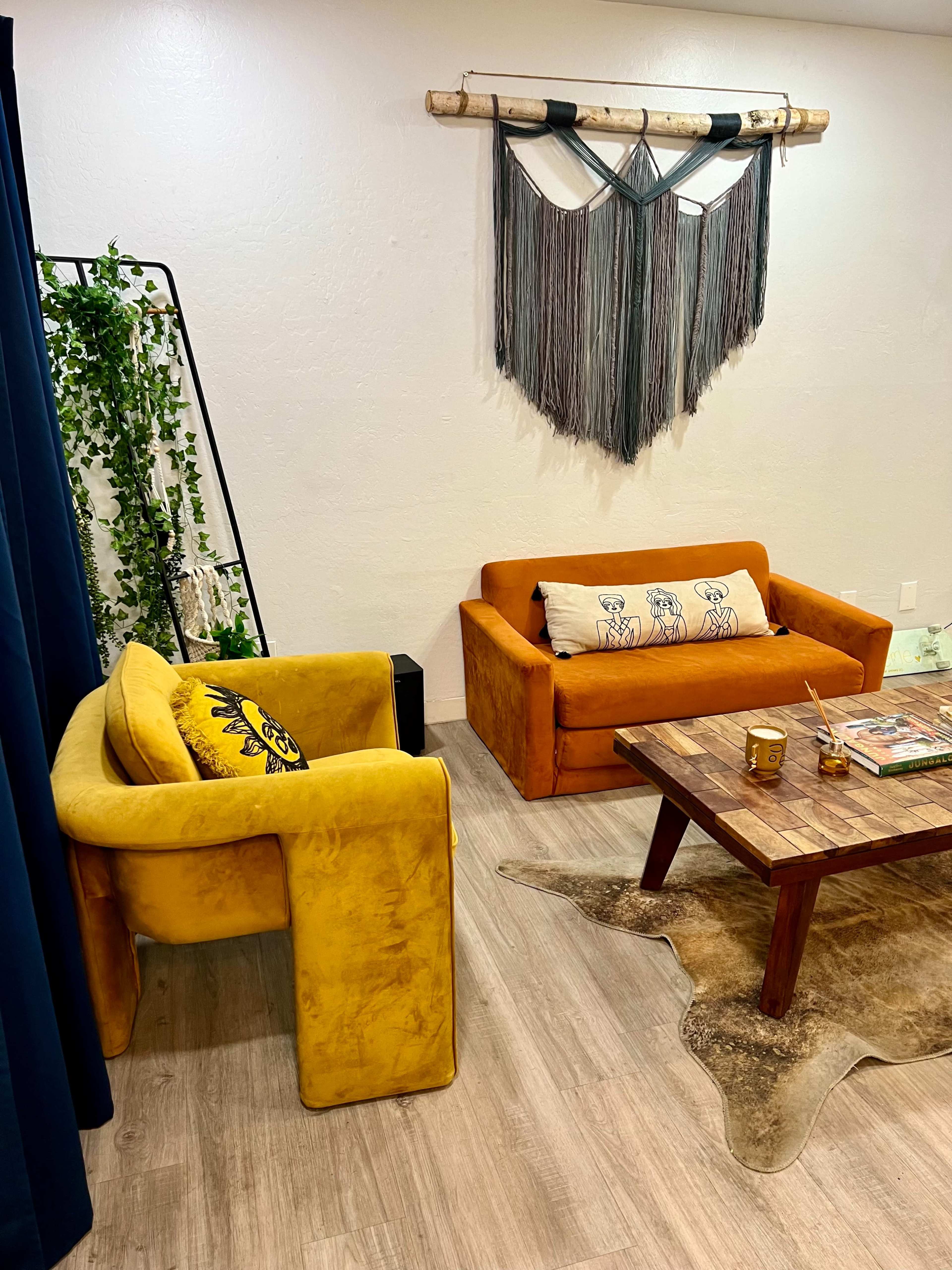 A cozy living space featuring two yellow sofas facing a wooden coffee table, with a decorative wall hanging above.