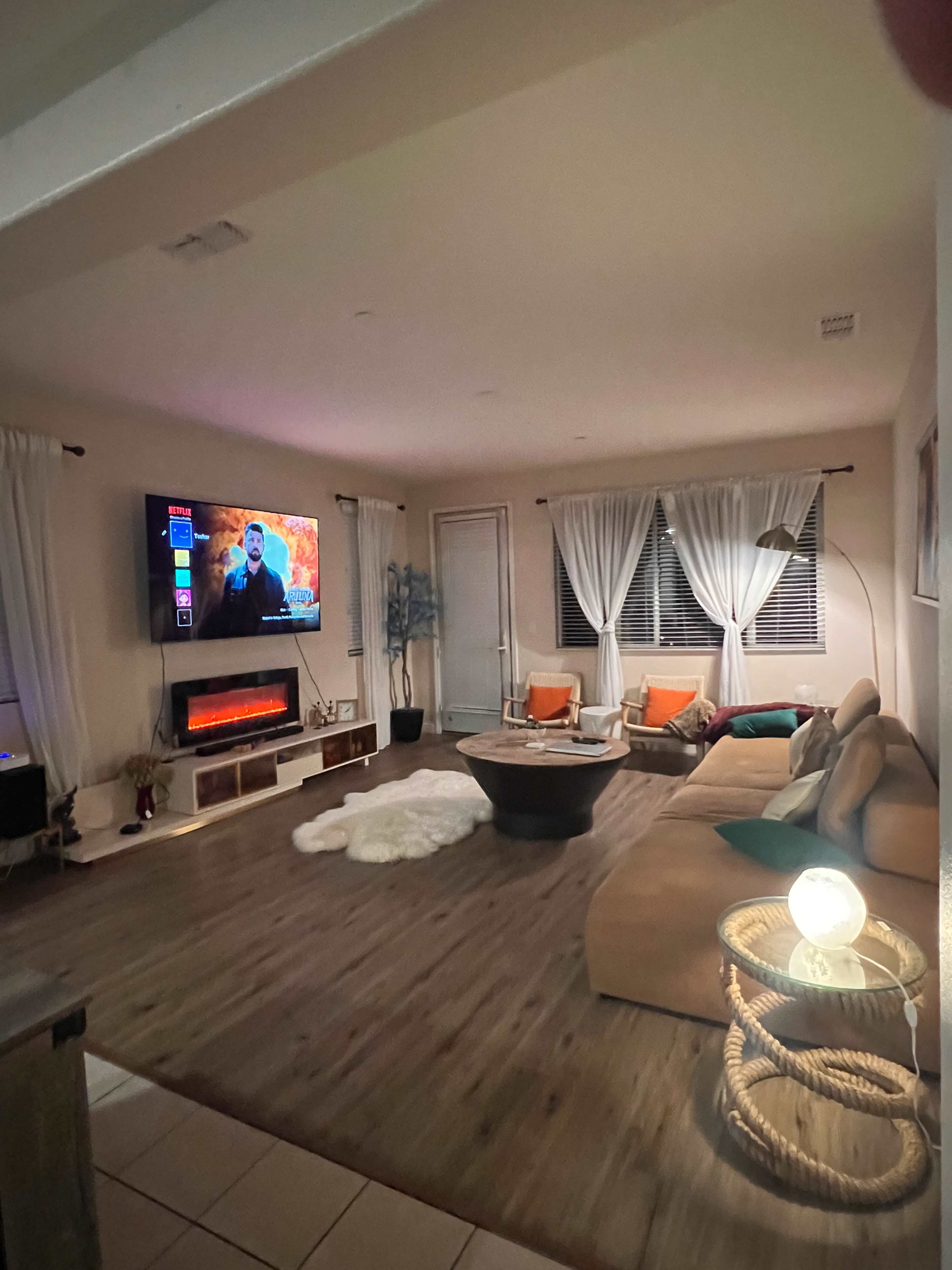The living room features a sectional sofa, a coffee table, an electric fireplace, and a wall-mounted television.