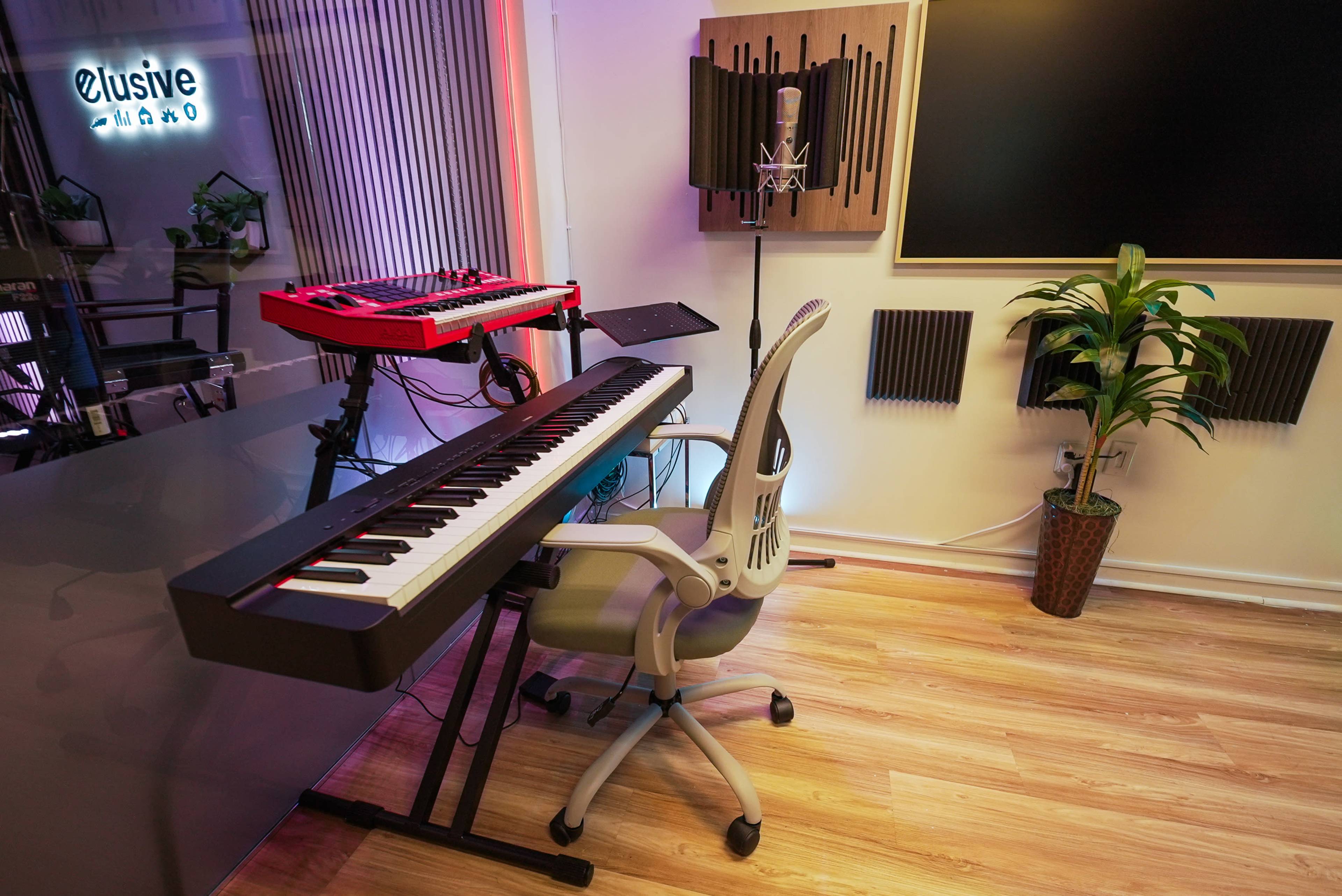 The image shows a modern music studio setup featuring a keyboard, a microphone on a stand, and soundproof panels on the walls.
