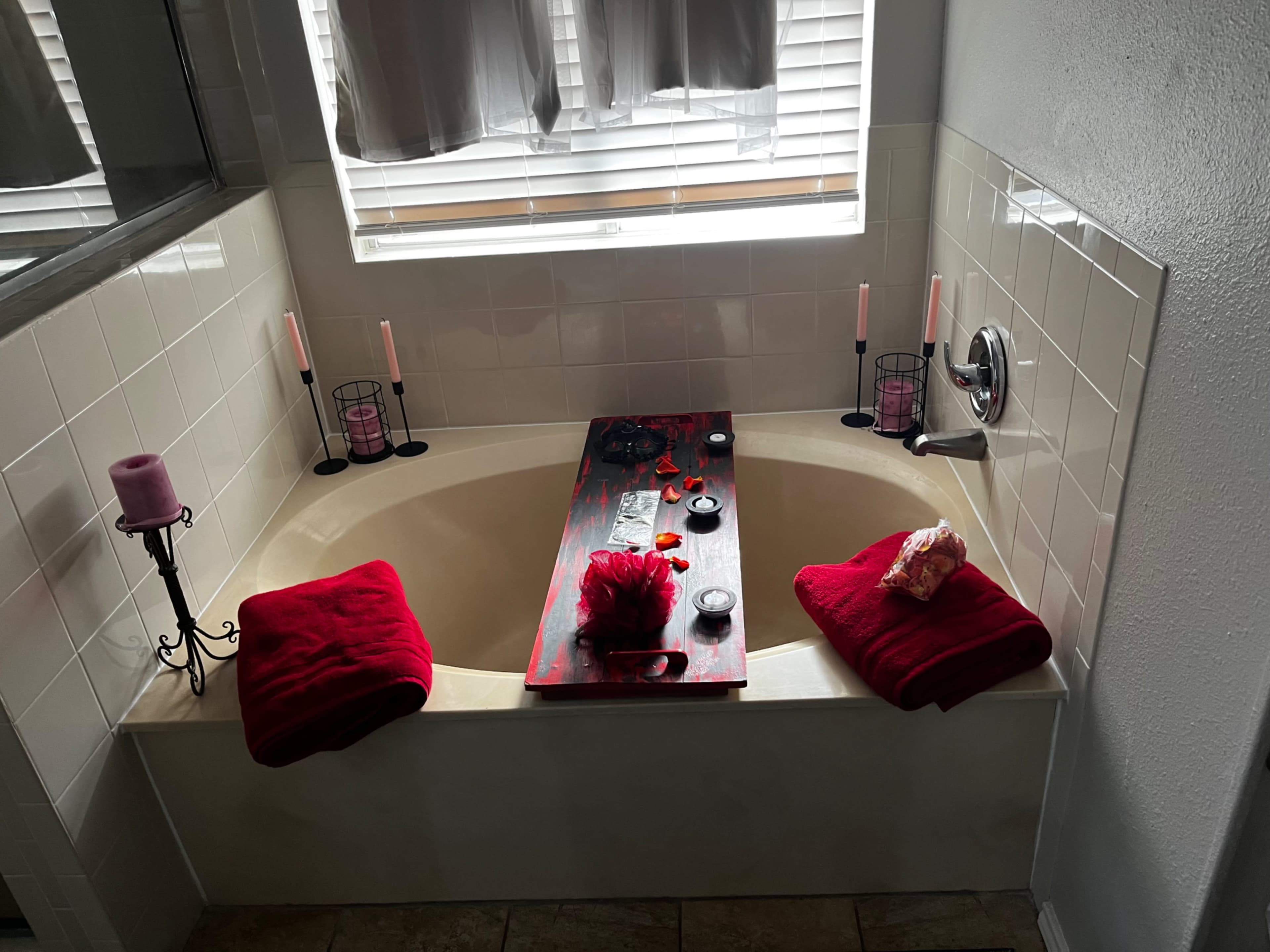 A bathroom with a bathtub surrounded by candles, towels, and decorative items.