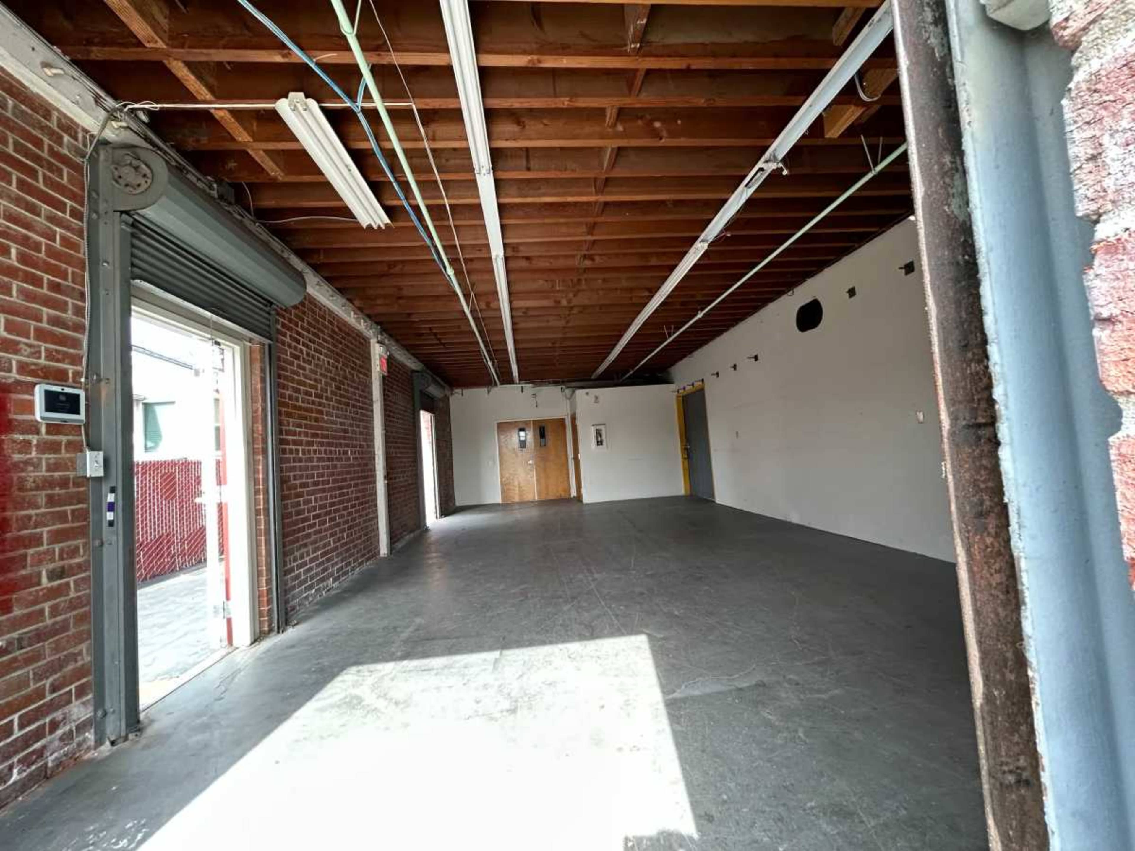 An empty, unfinished interior space with exposed wooden beams and brick walls.