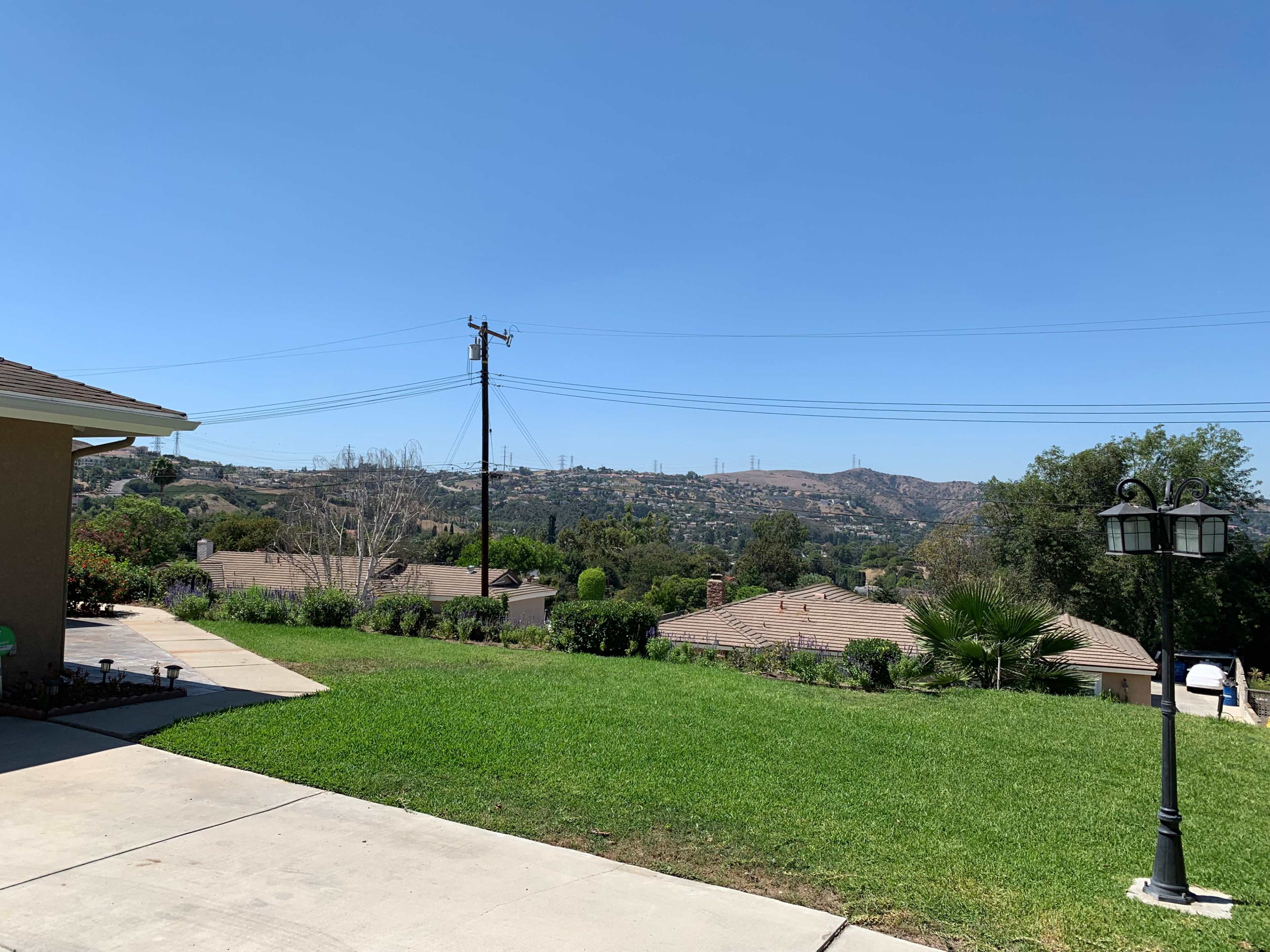 The image shows a clear sky over a residential area with houses and hills in the background.