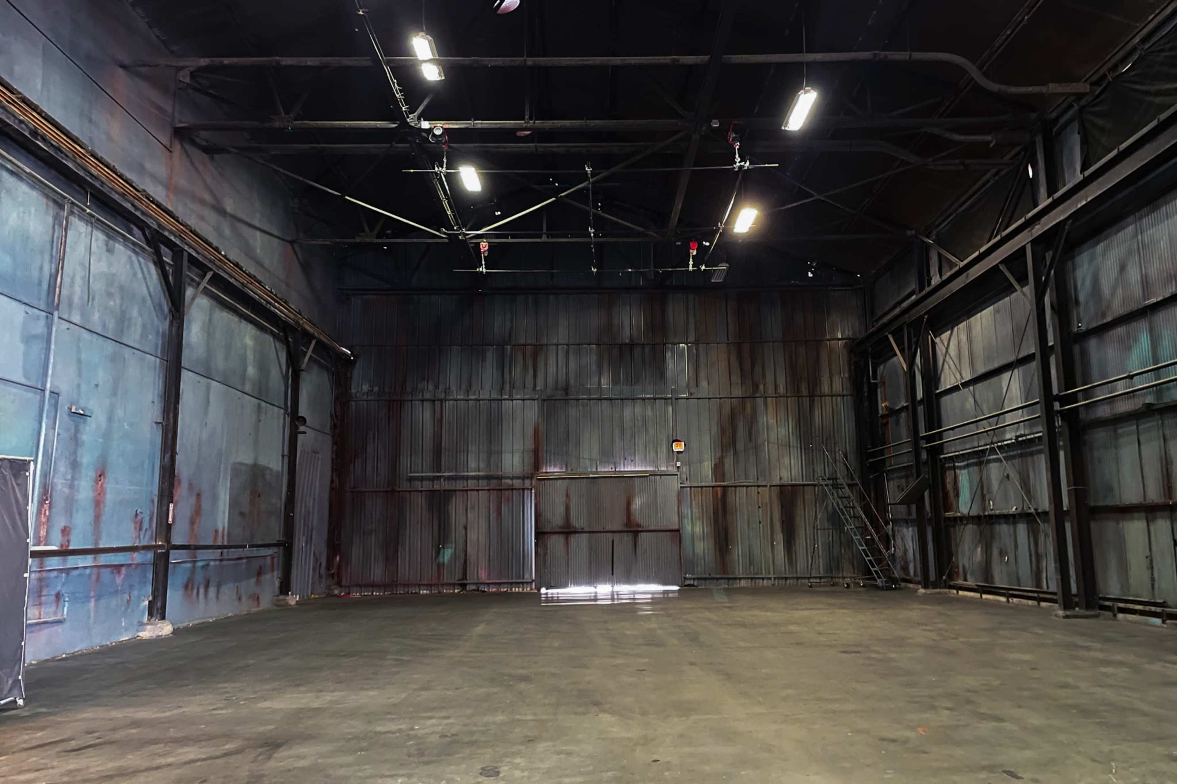 A large, empty warehouse interior with metal walls and a concrete floor.