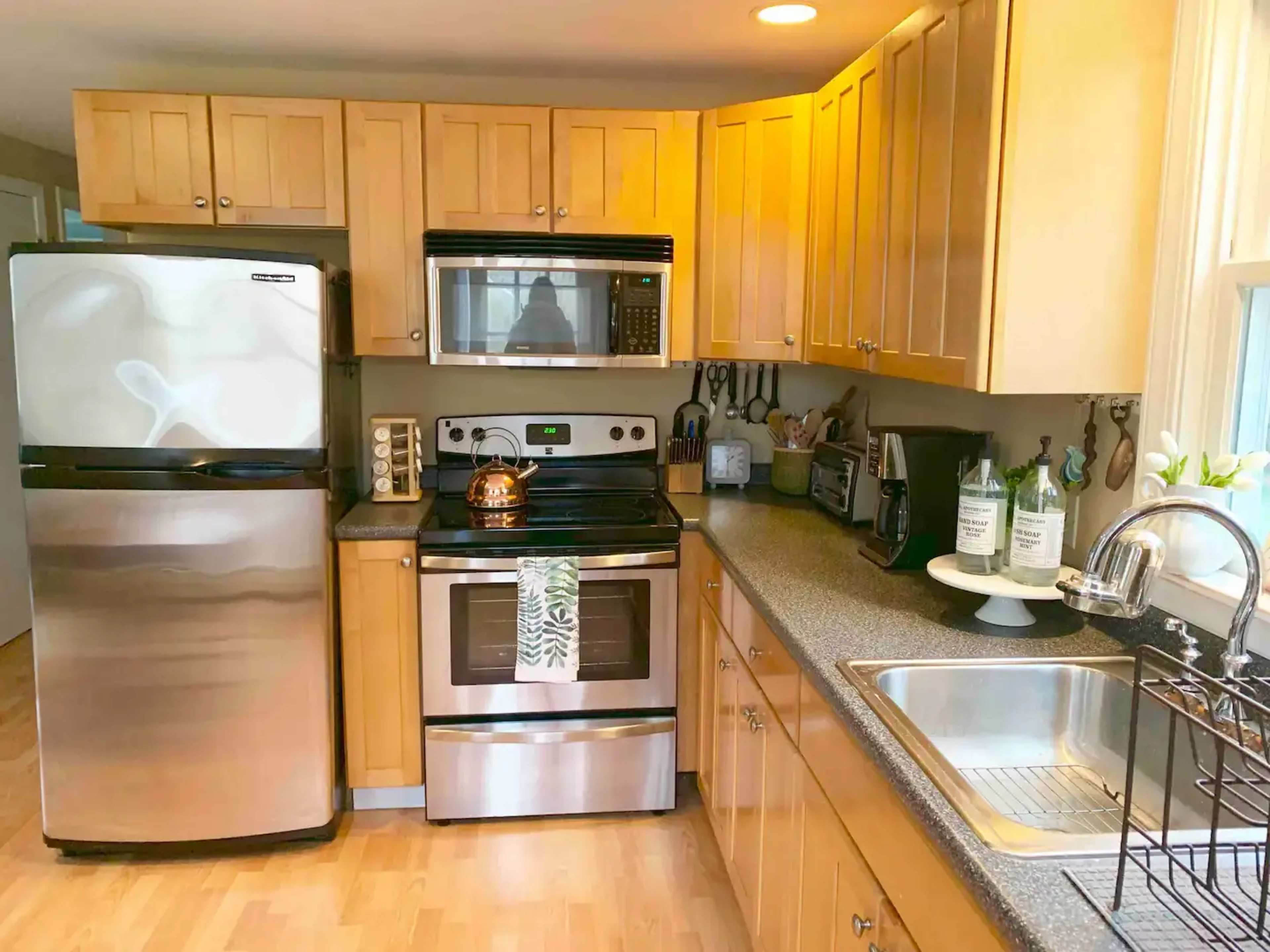 A modern kitchen features stainless steel appliances, wooden cabinetry, and a countertop with a sink and decorative items.