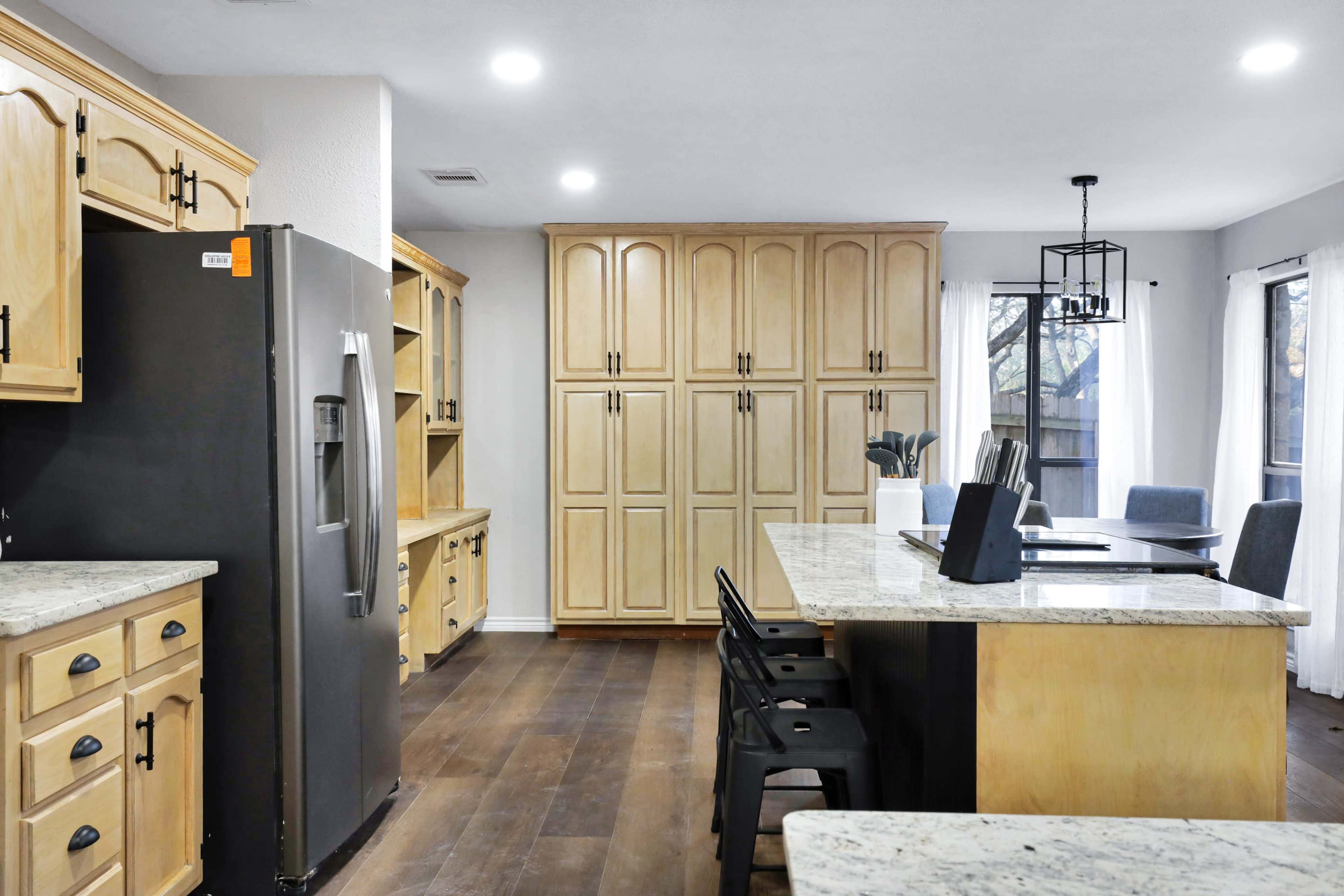 A modern kitchen featuring wooden cabinetry, a large island with seating, granite countertops, and stainless steel appliances.