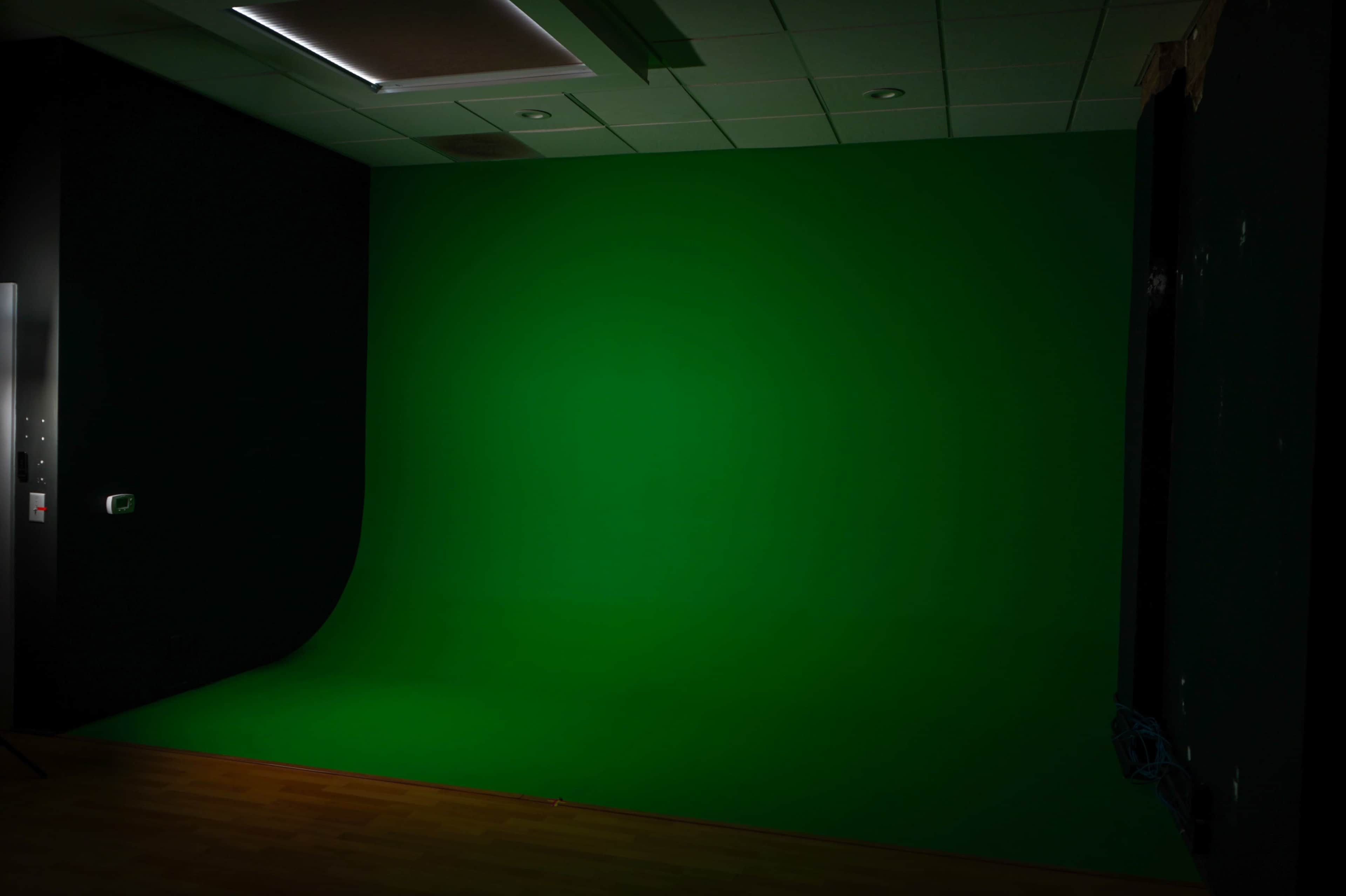 A studio room with a bright green backdrop and wooden flooring.