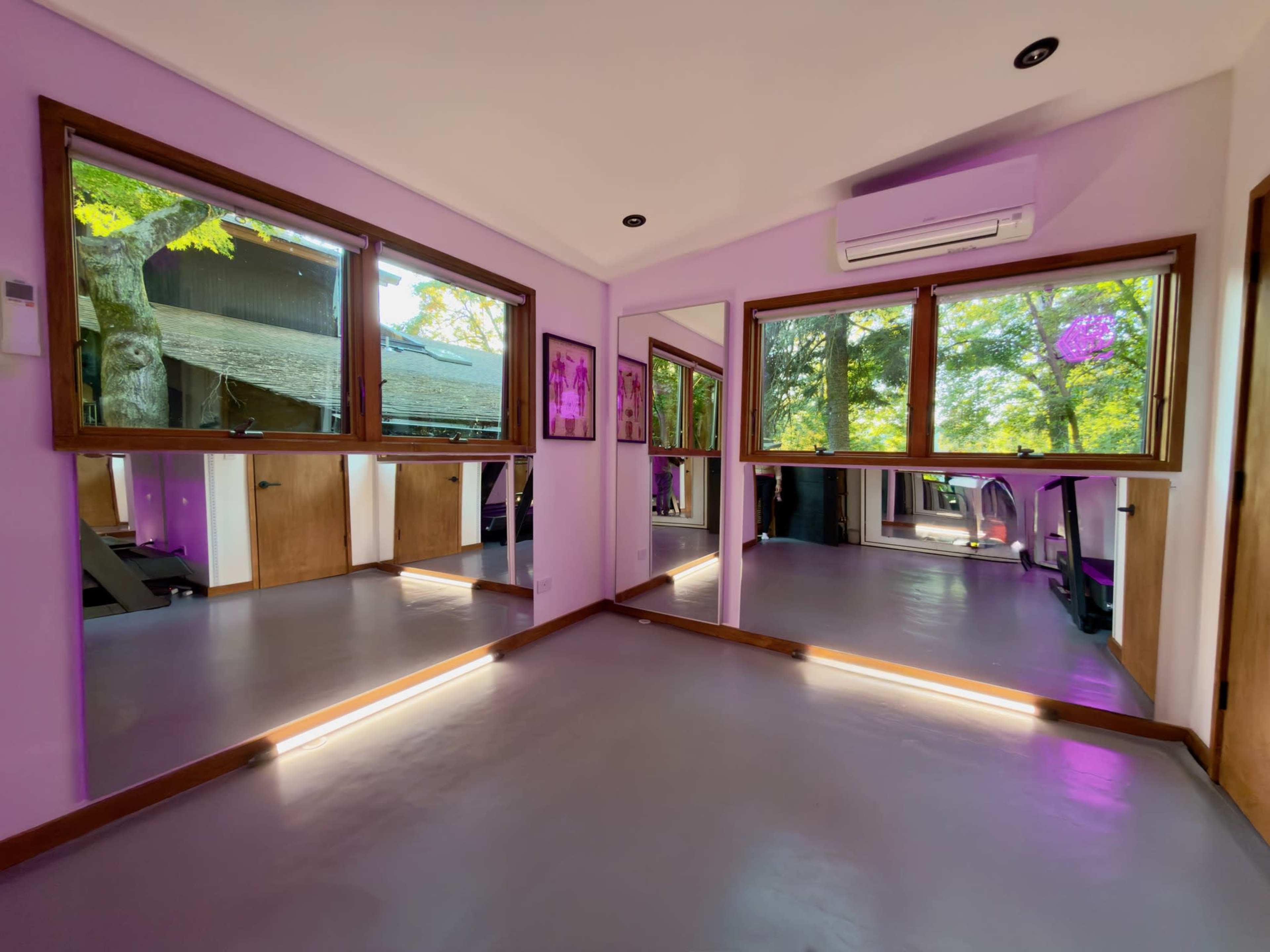 The image shows a modern room with two large windows and mirrors, featuring a light purple color scheme and wooden accents.