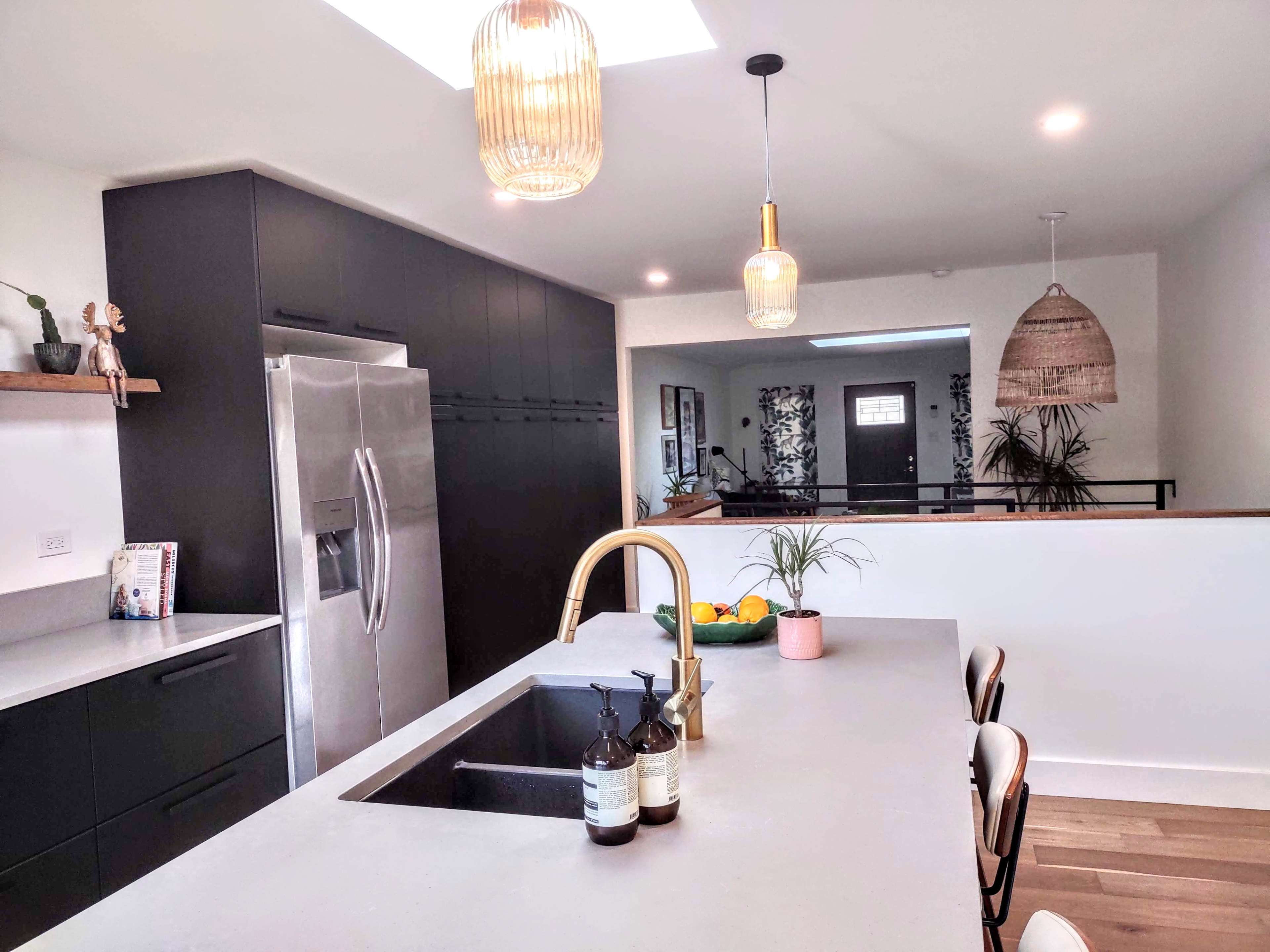 A modern kitchen featuring a large island with a sink, stainless steel appliances, and pendant lighting above.