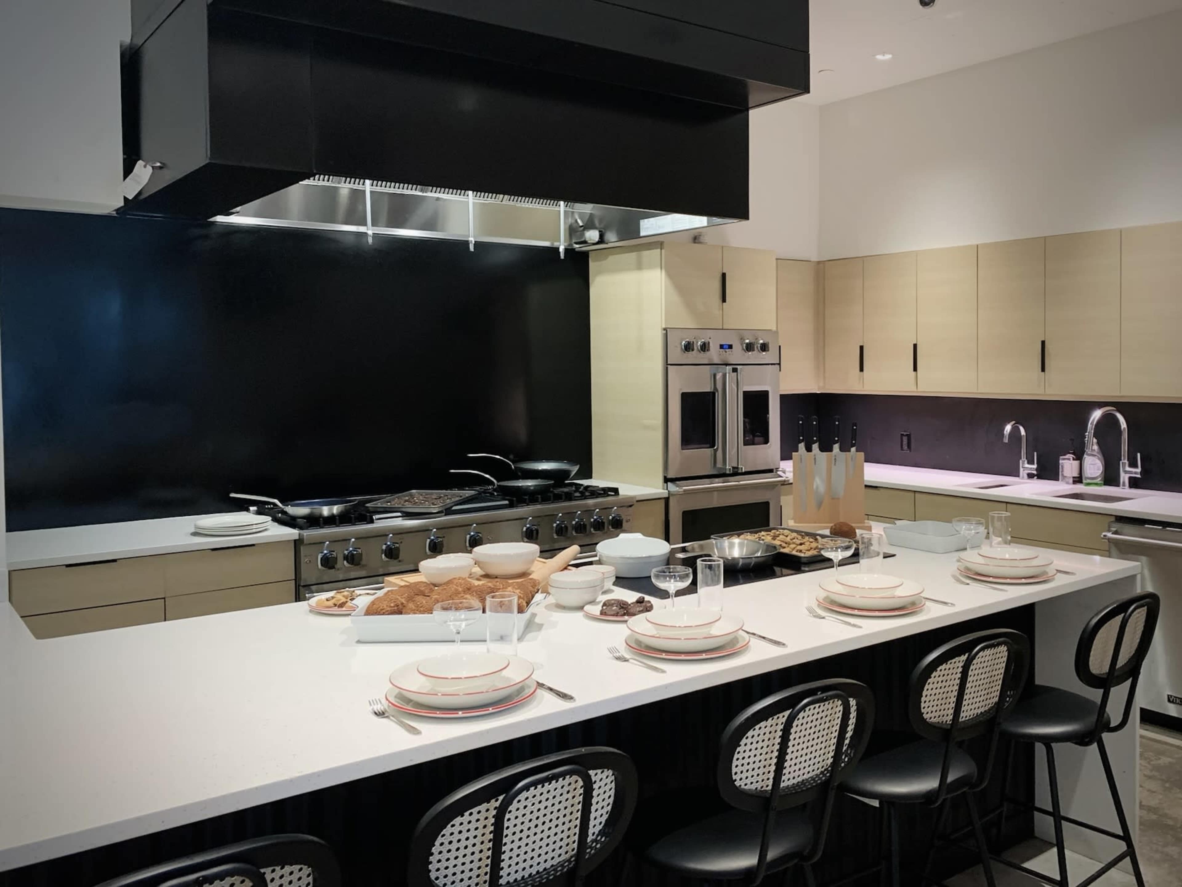 A modern kitchen features a large cooking range, minimalist cabinetry, and a dining area with a table set for breakfast.