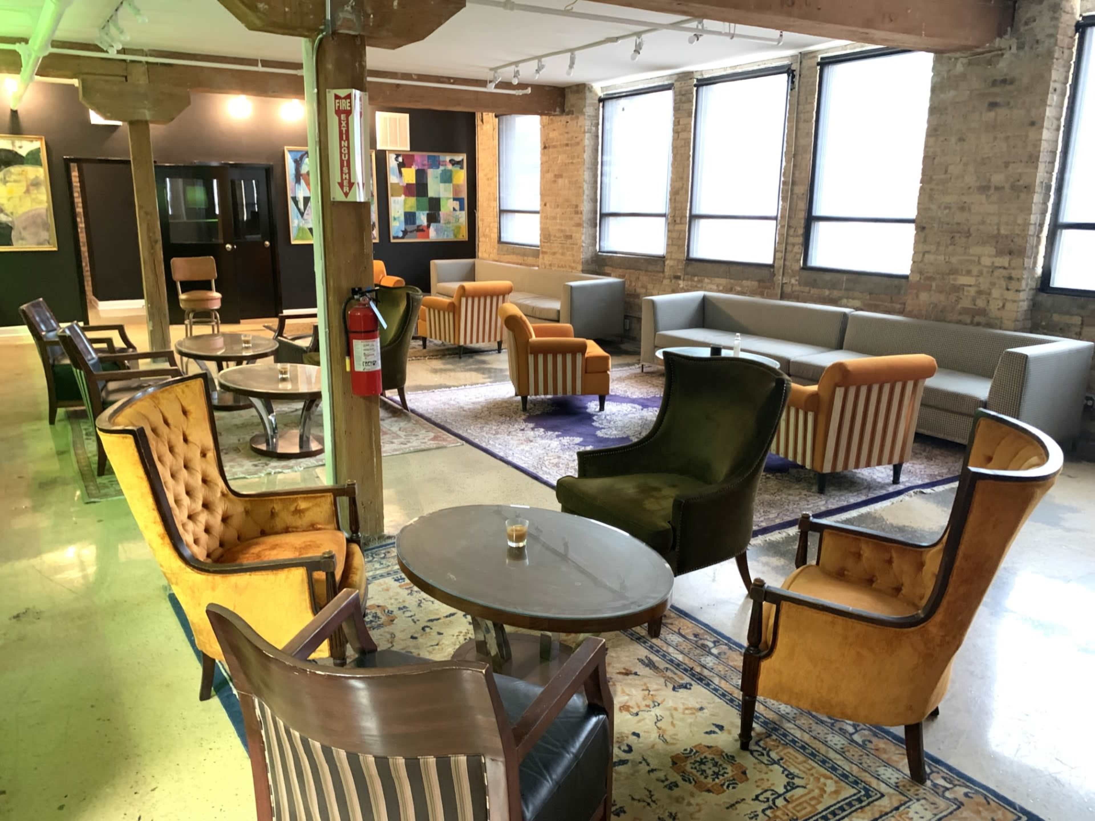 A spacious lounge area furnished with various seating arrangements, including armchairs and sofas, along with a central coffee table and decor on the walls.