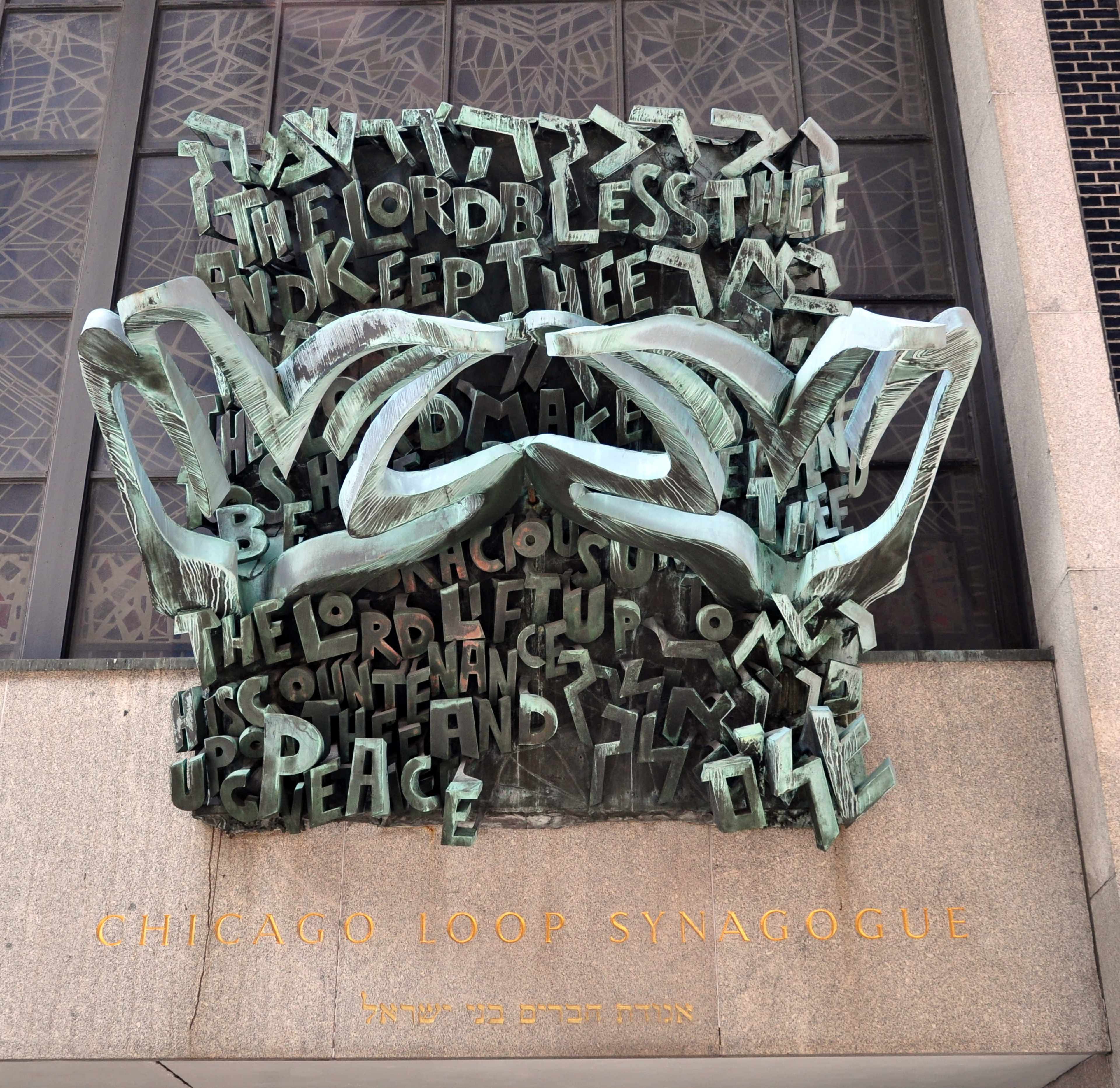 The image shows a bronze relief sculpture with Hebrew text and the words "CHICAGO LOOP SYNAGOGUE" displayed on a building facade.