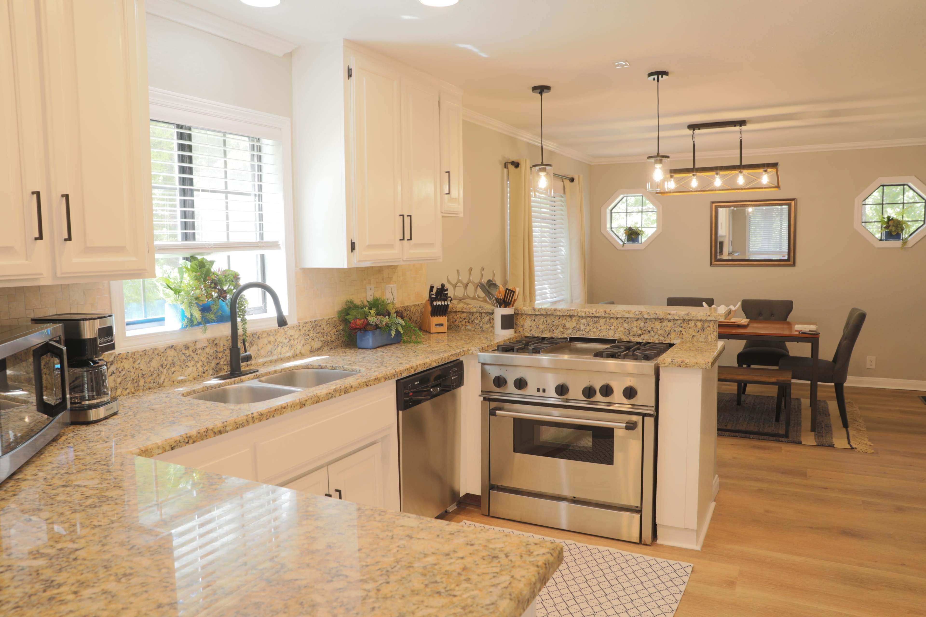 The image shows a modern kitchen with granite countertops, stainless steel appliances, and a dining area visible in the background.