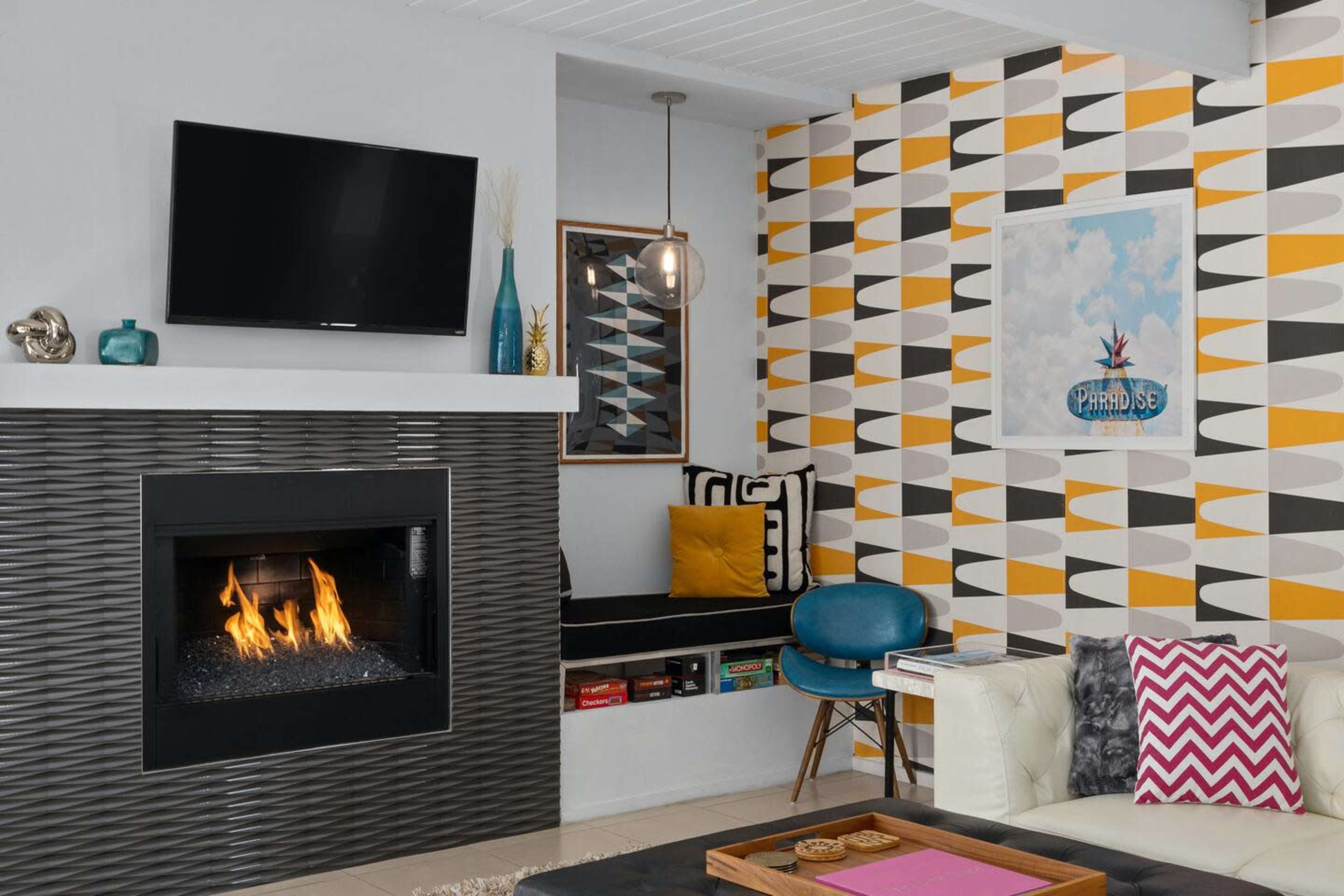 A modern living room featuring a black fireplace, a television mounted on the wall, and patterned wallpaper in shades of yellow and gray.