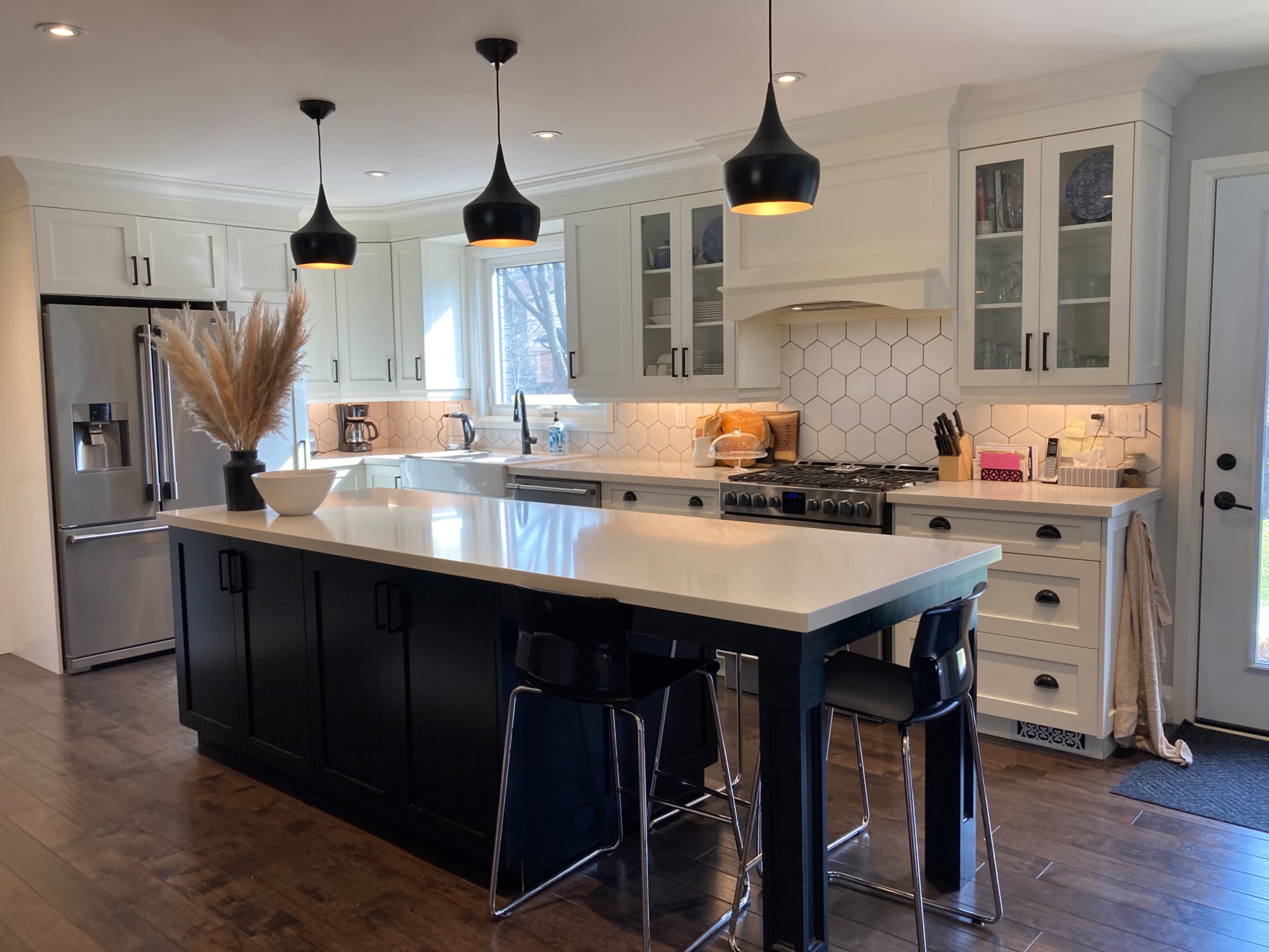 The kitchen features a large central island with a dark base, white cabinetry, modern appliances, and pendant lighting.
