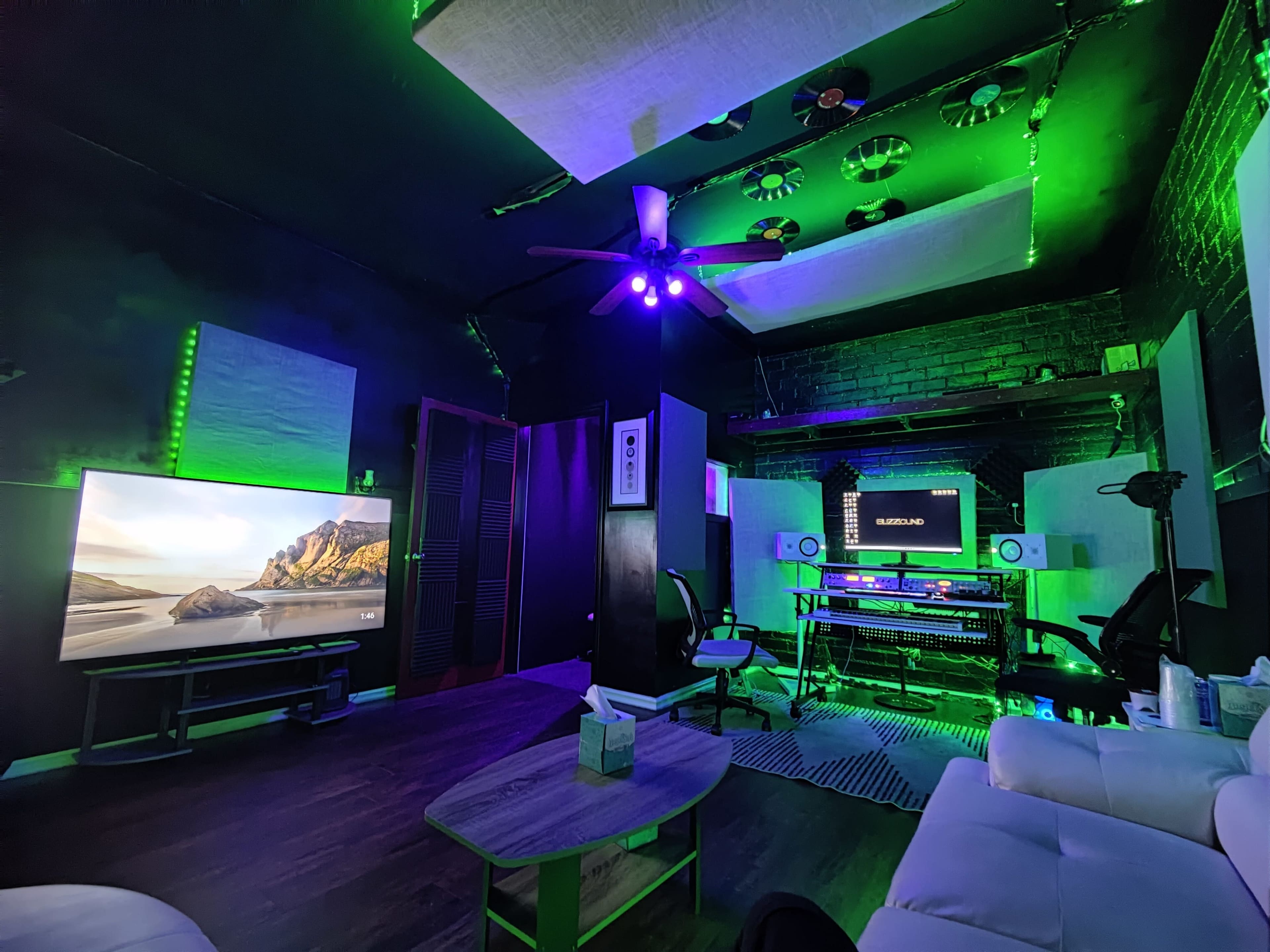 The image shows a modern room with a large television, computer setup, and various green LED lights illuminating the space.