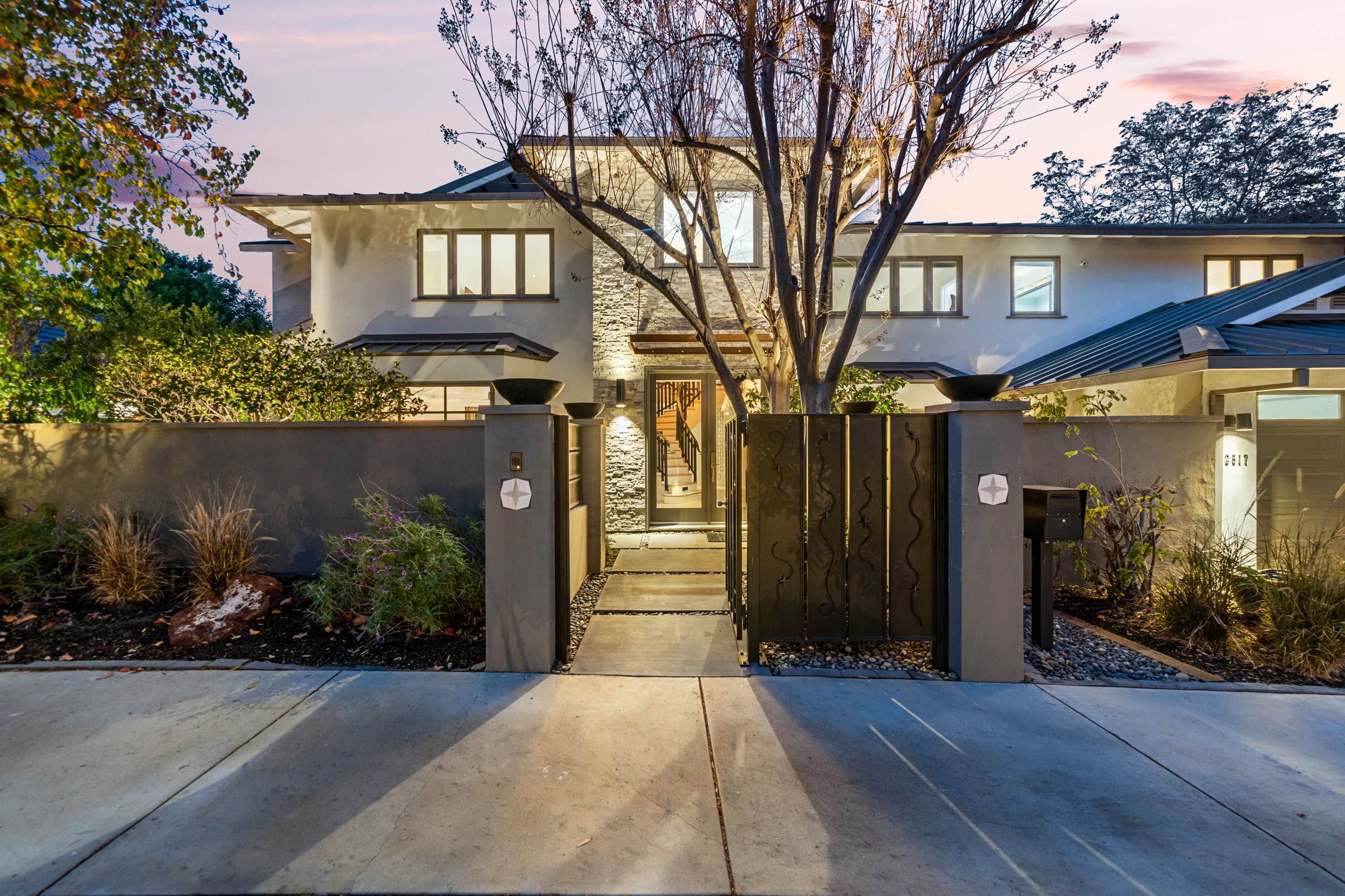 A modern two-story house features a stone accent wall, landscaped front yard, and a pathway leading to the entrance.