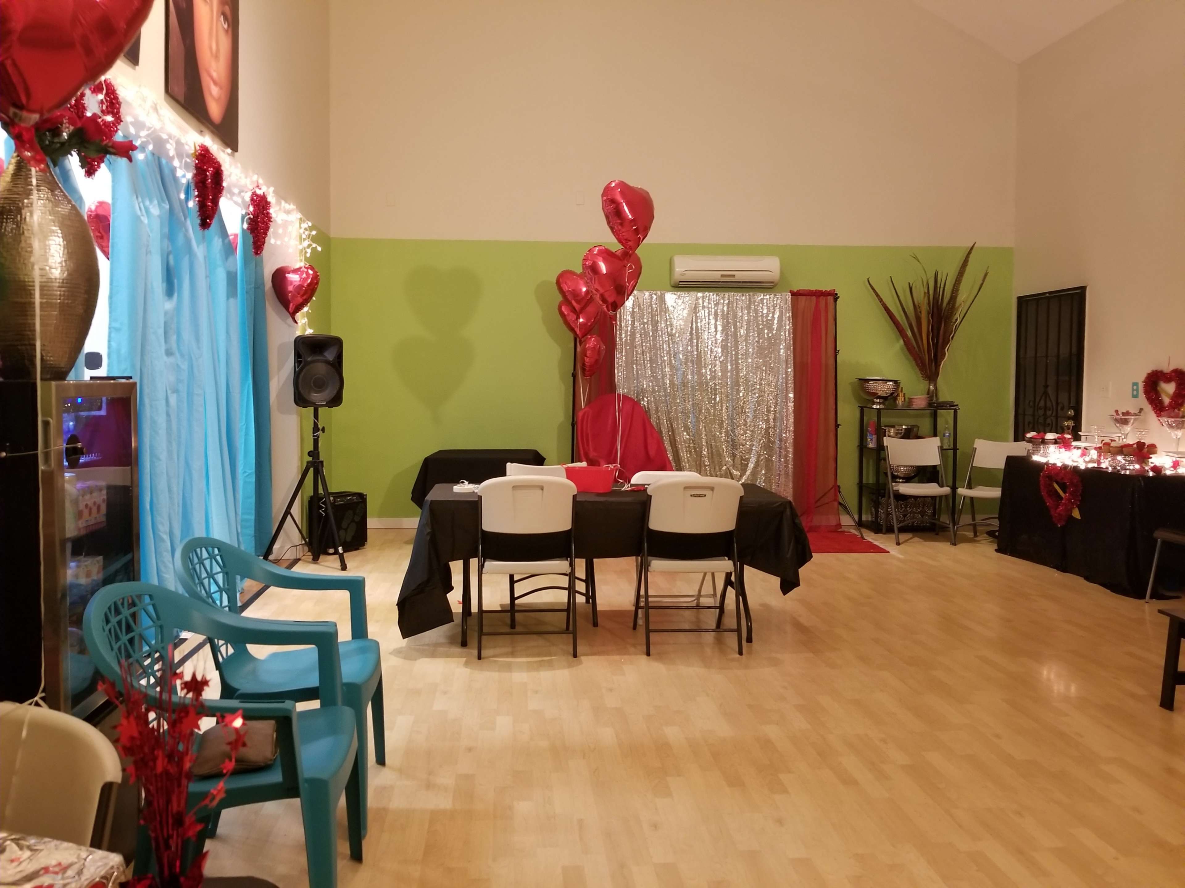 The scene features a decorated event space with tables set for guests, heart-themed decorations, and a backdrop made of sequins.
