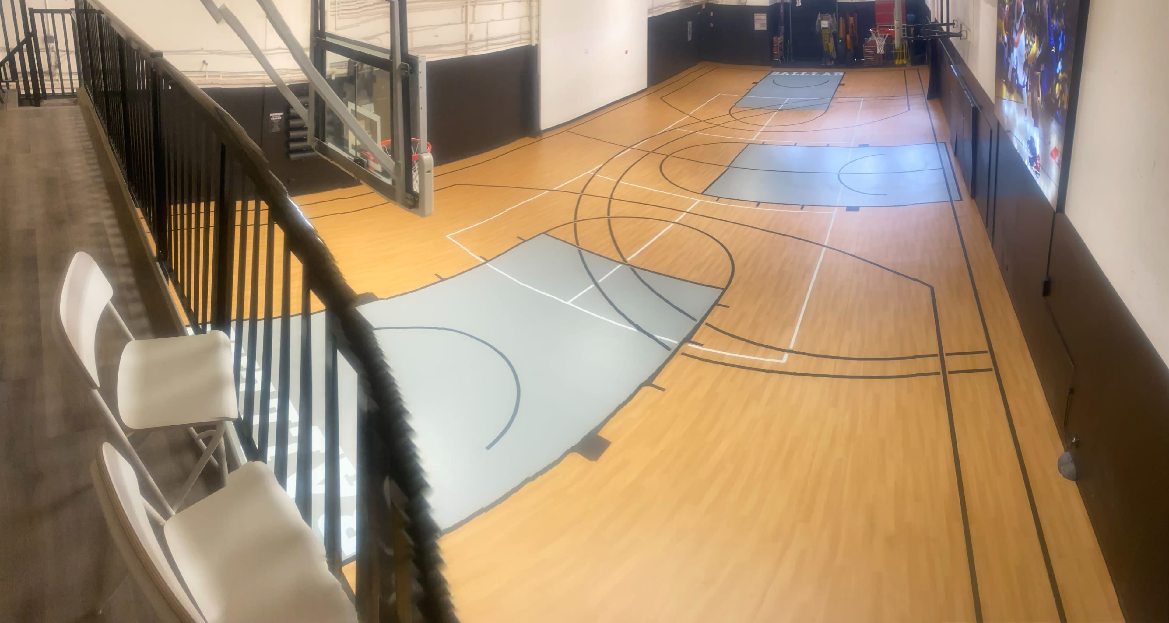 An indoor sports facility with wooden flooring featuring multiple basketball court outlines and areas marked in gray.