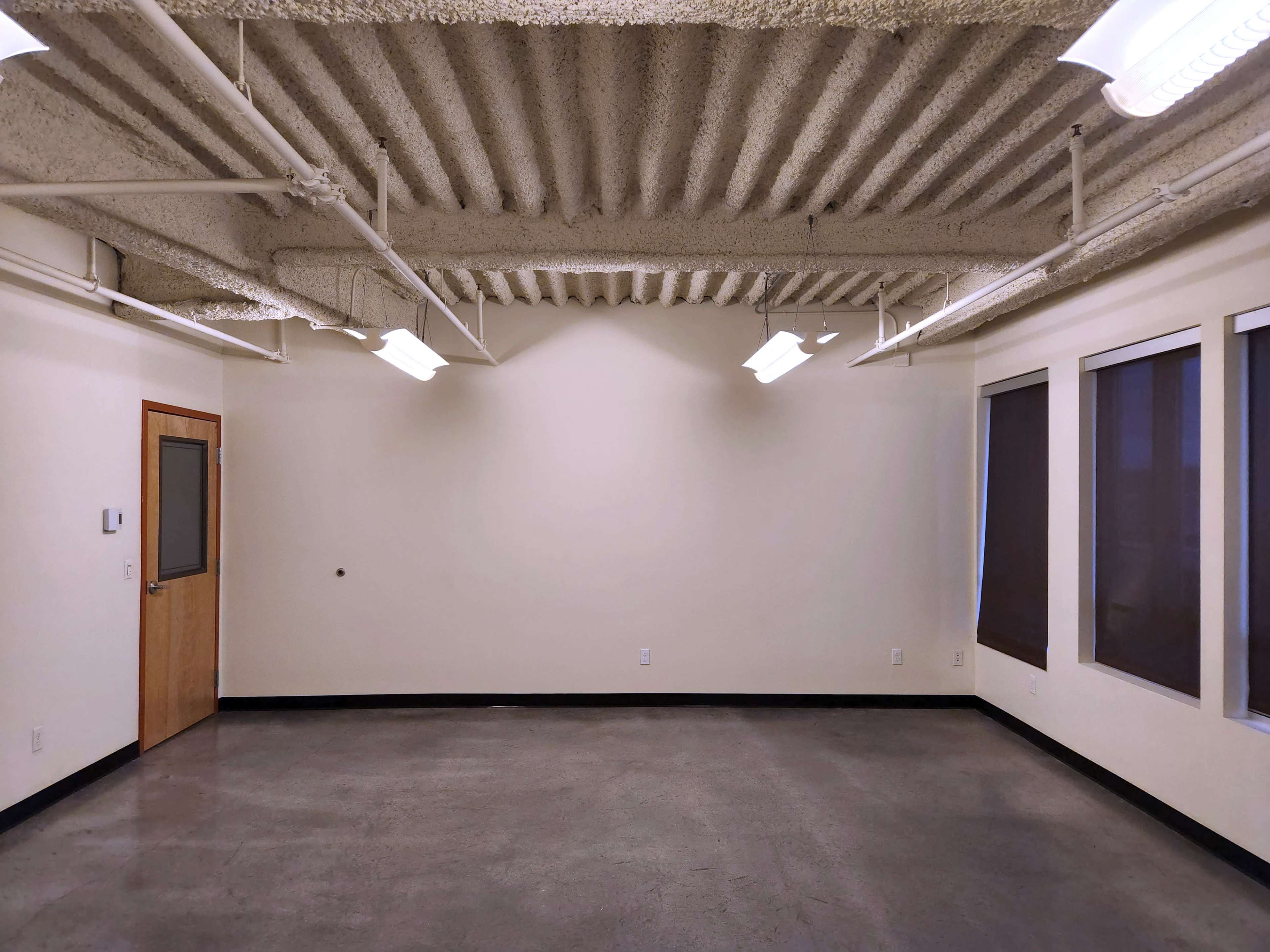 An empty room with a concrete floor, textured ceiling, and a door on one side.