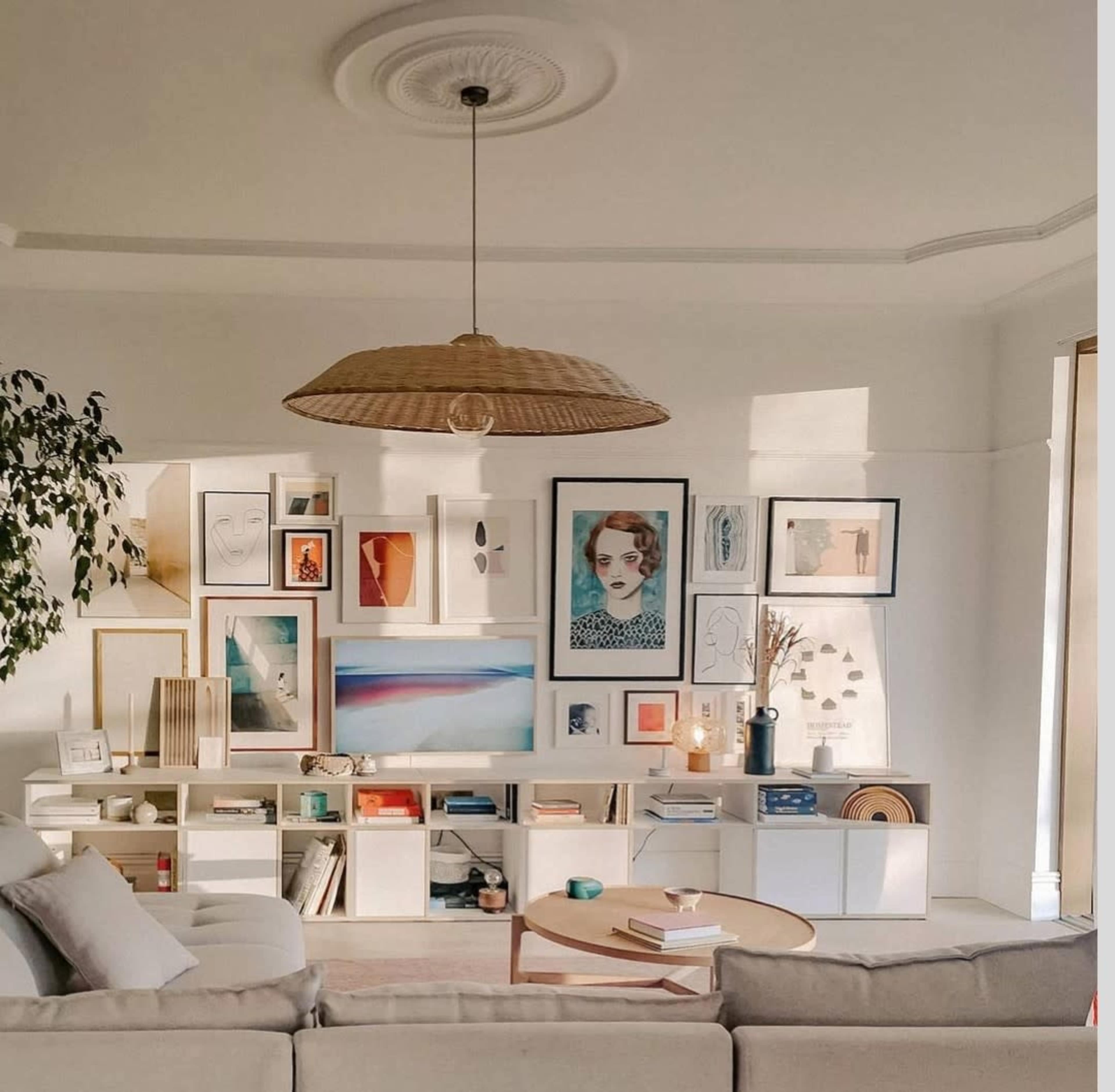 A well-organized living room featuring a large beige sofa, a wooden coffee table, and a gallery wall adorned with various framed artworks.