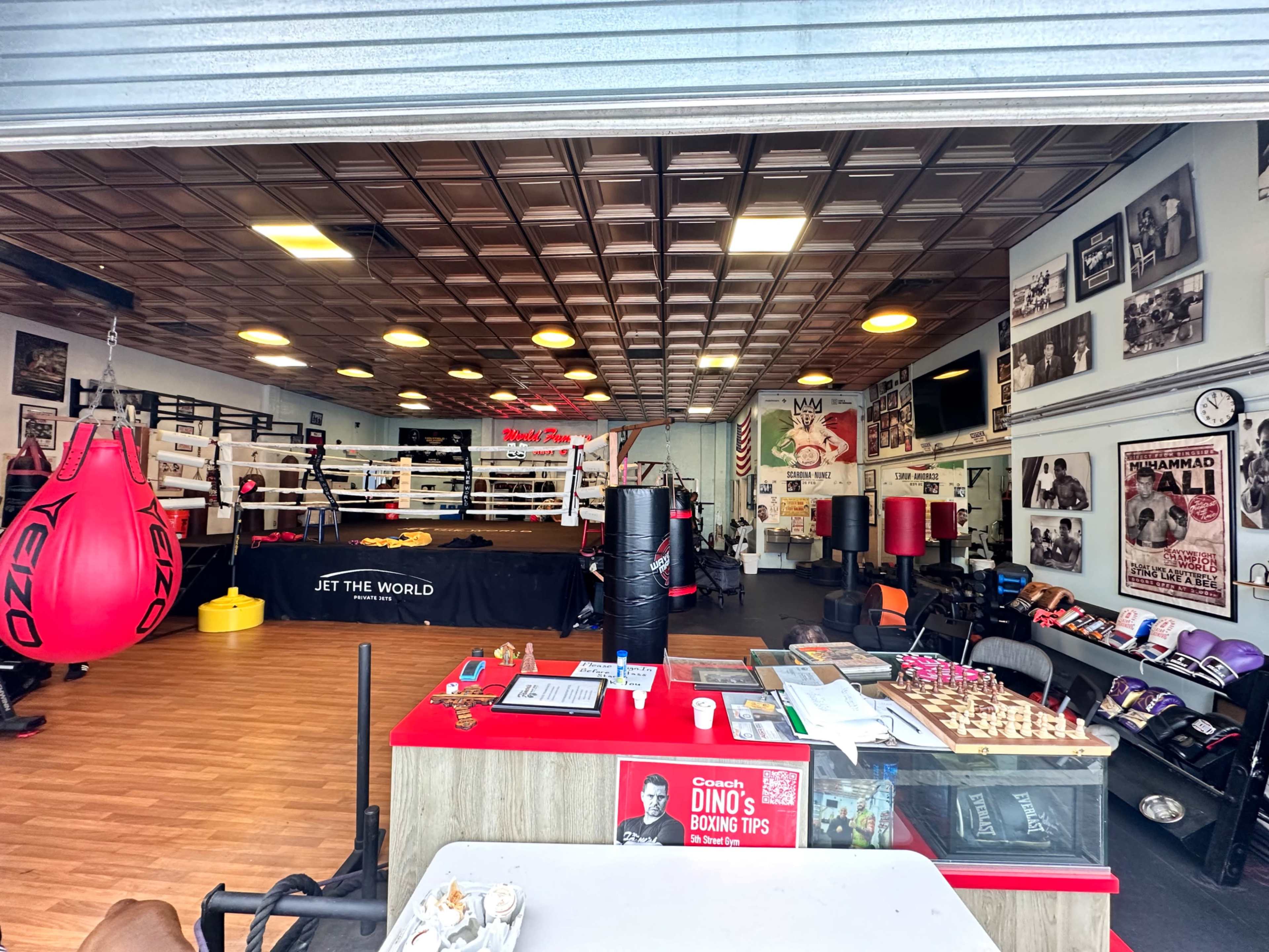 A boxing gym with a reception area, training ring, and various boxing equipment displayed on the walls and shelves.