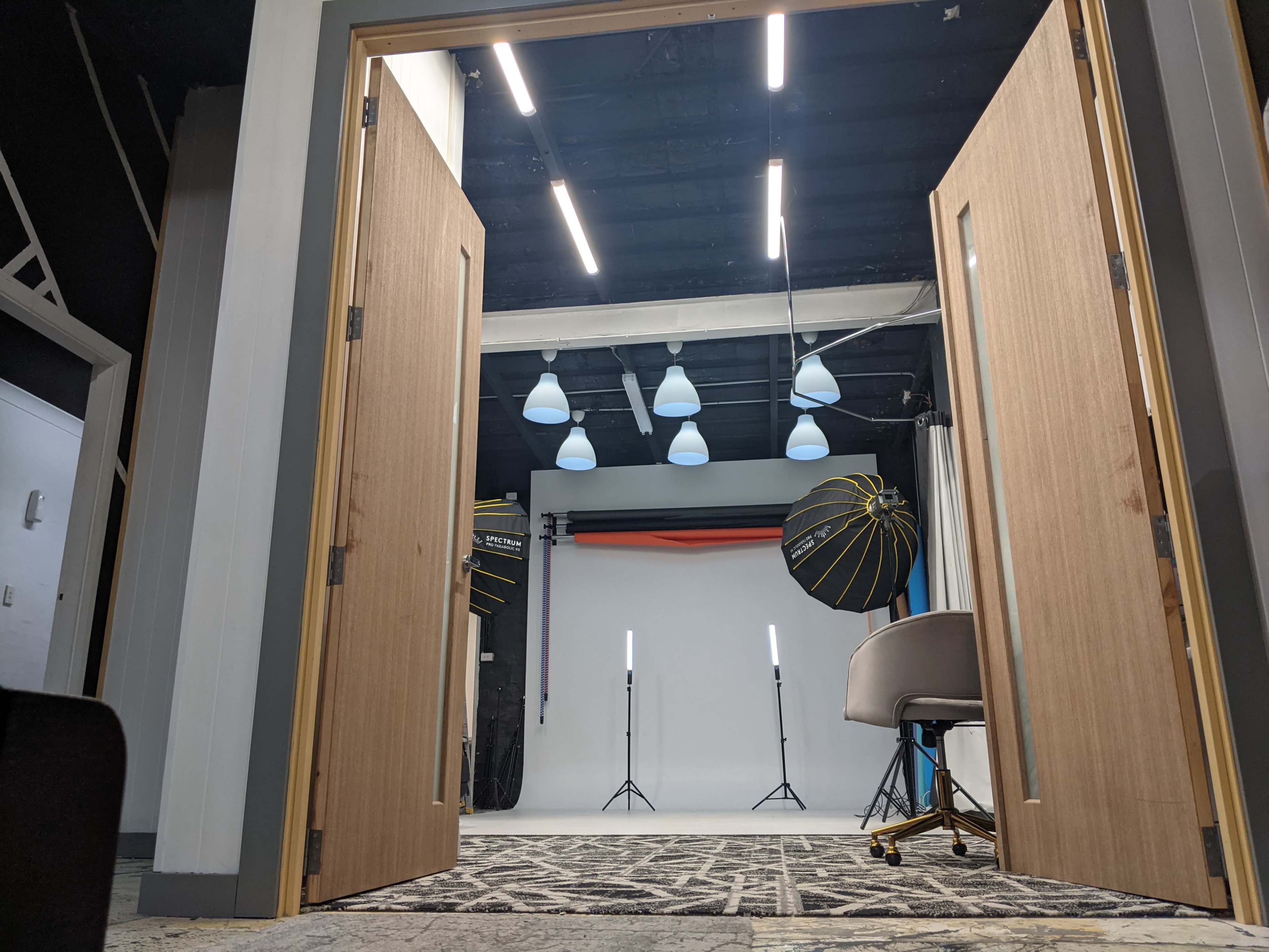 An open door leading into a photography studio with lighting equipment and a backdrop set up for a photoshoot.