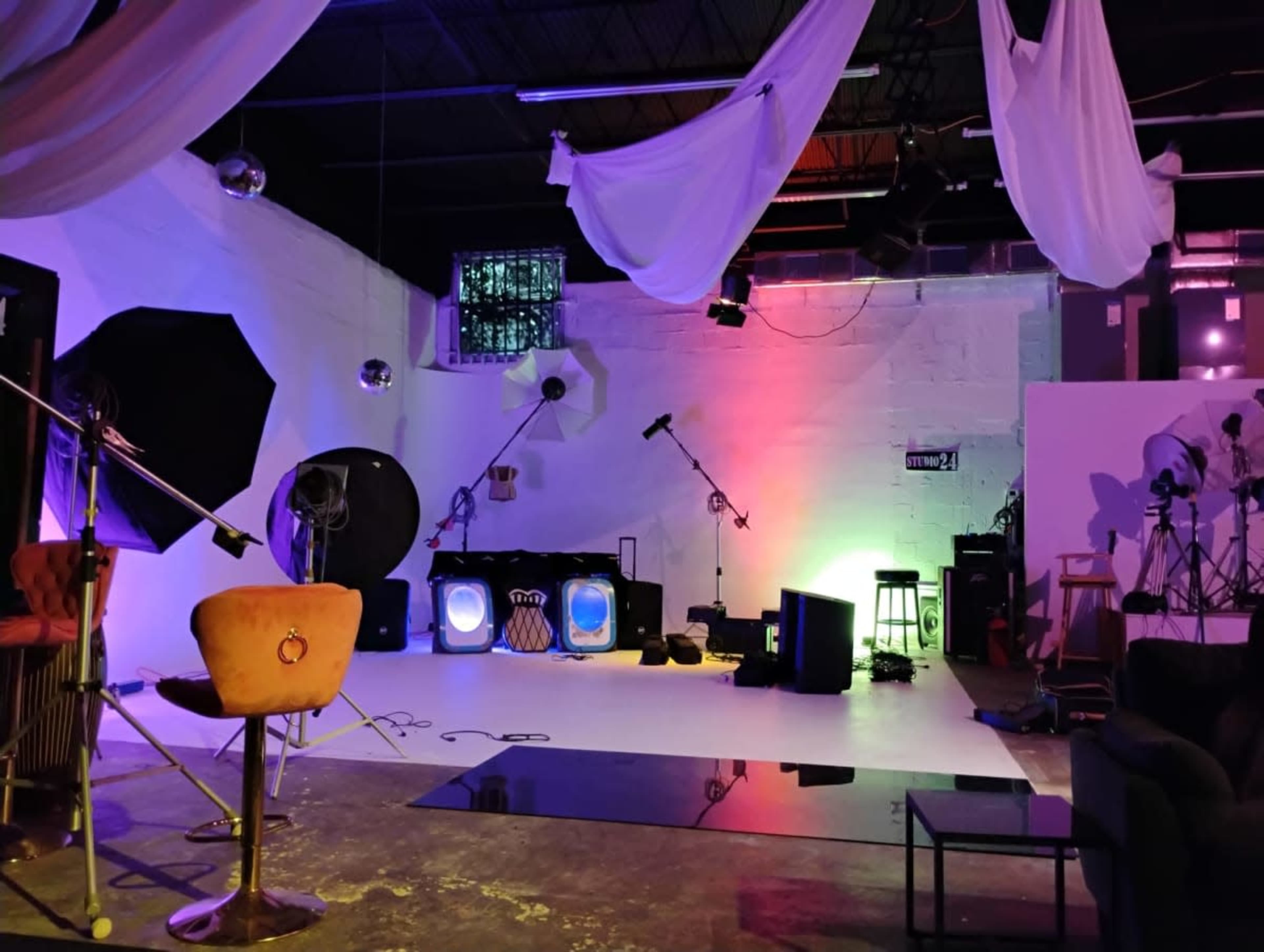 The image shows a photography studio equipped with various lights, backdrops, and props, creating a colorful and artistic setup.