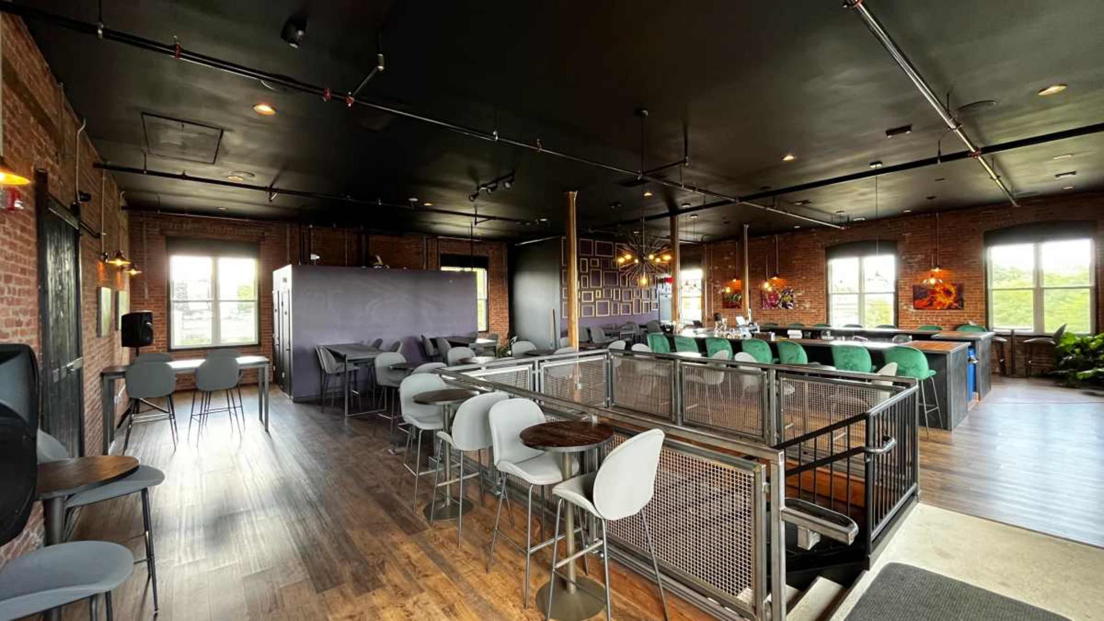 A spacious, modern lounge area with brick walls, various seating options, and large windows.