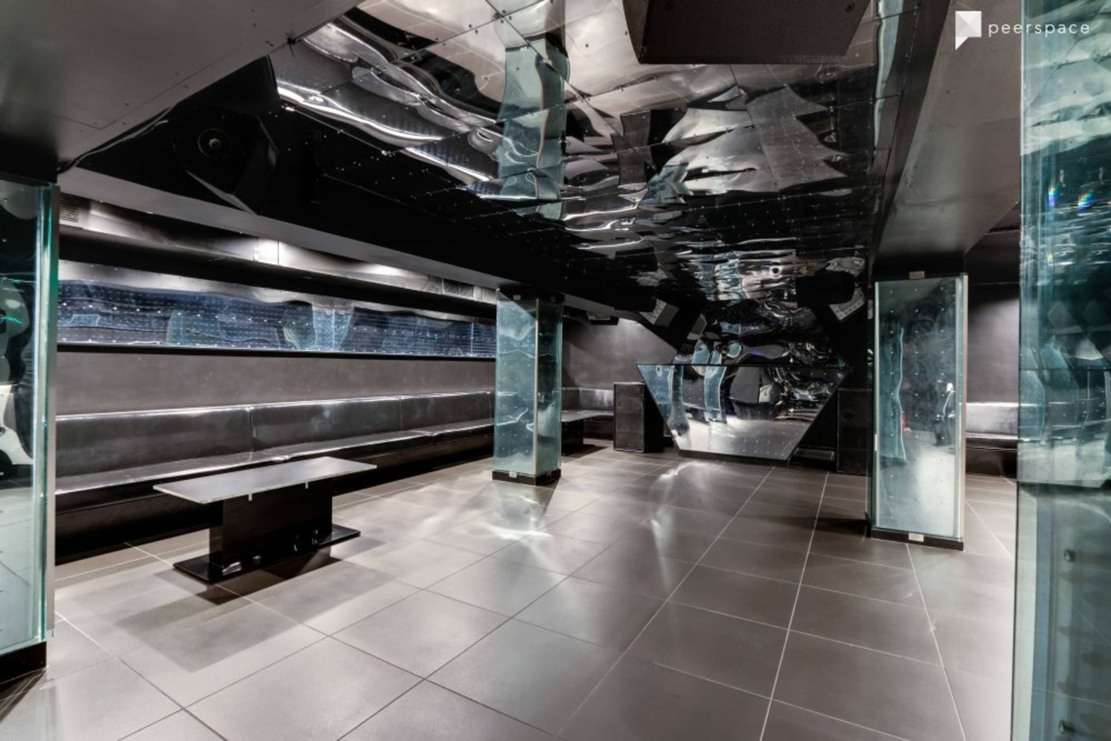 A modern, empty interior space with sleek black and mirrored surfaces, and a table in the center.