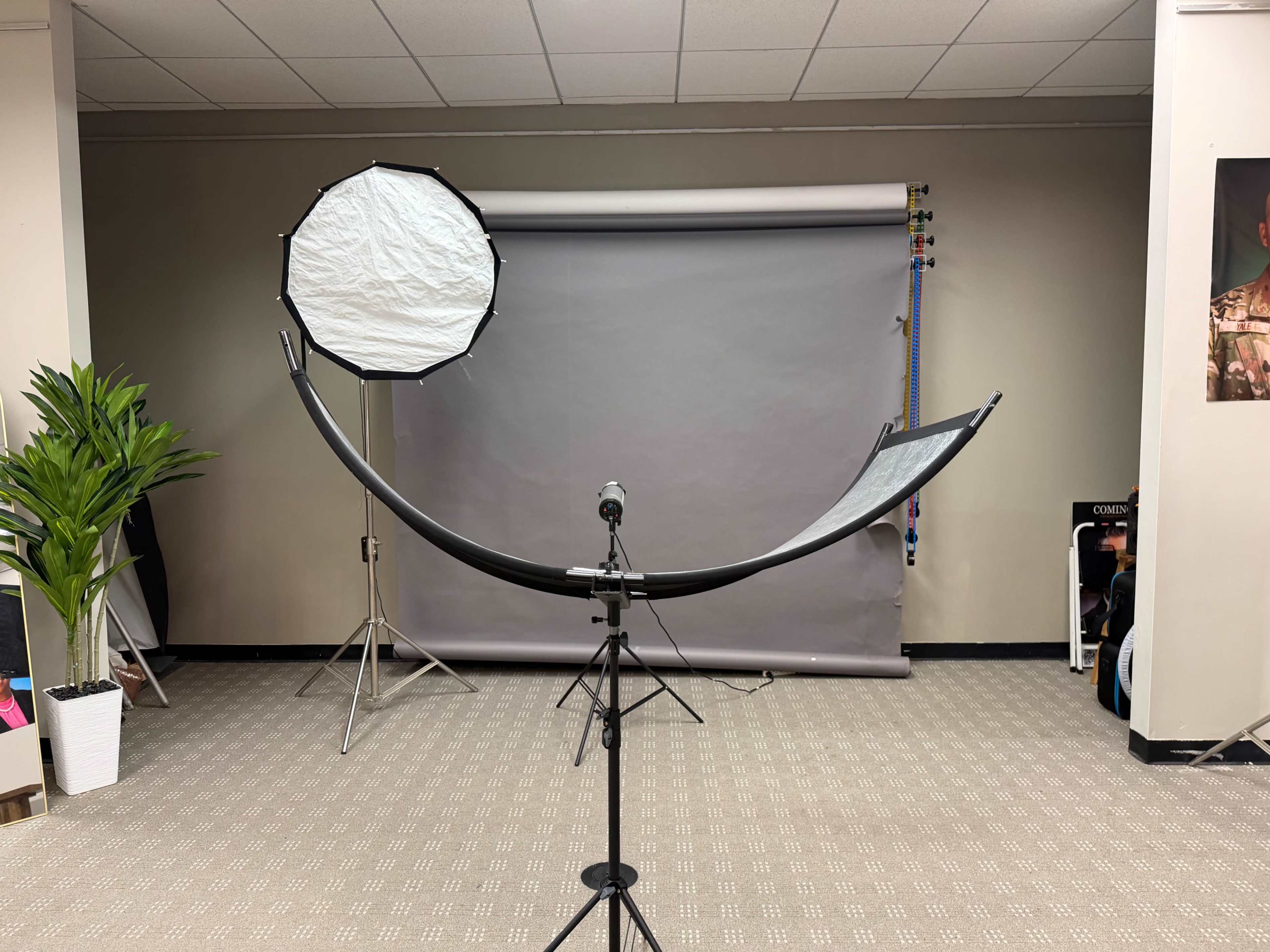 The image shows a photography studio setup featuring a large softbox, a seamless backdrop, and a microphone on a stand.