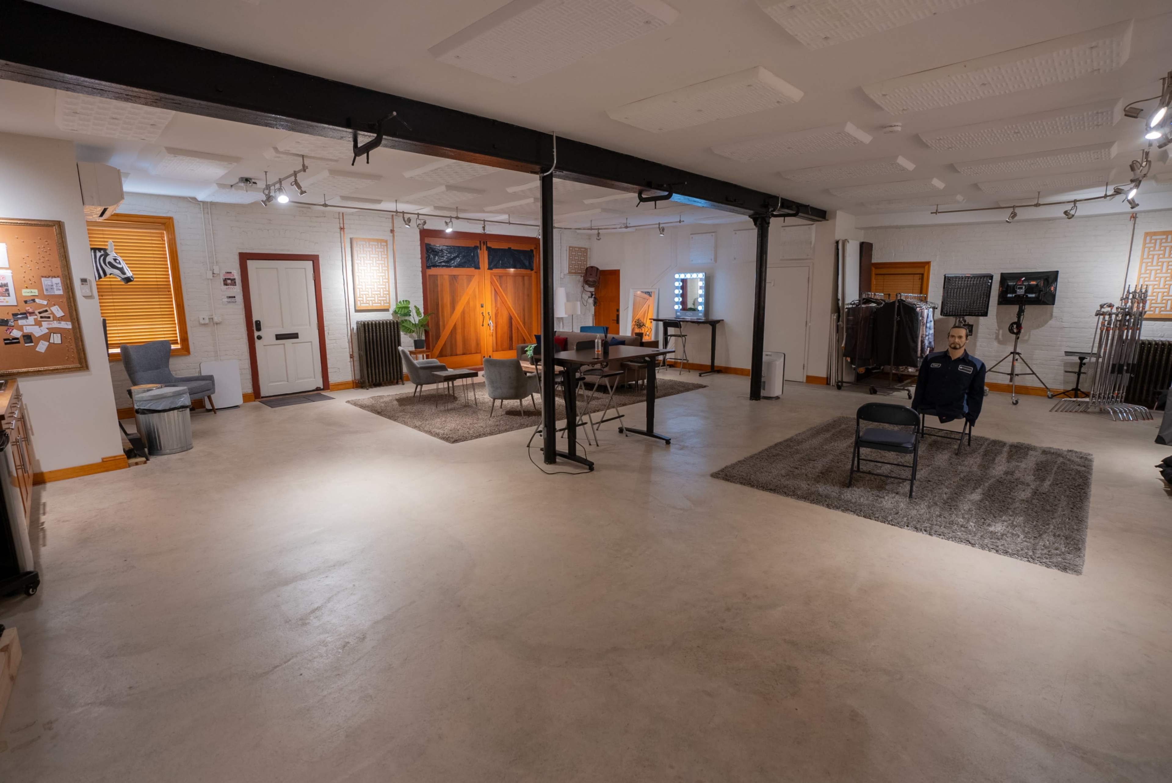A spacious room with concrete flooring, featuring a seating area with chairs, a table, and various decor items along the walls.