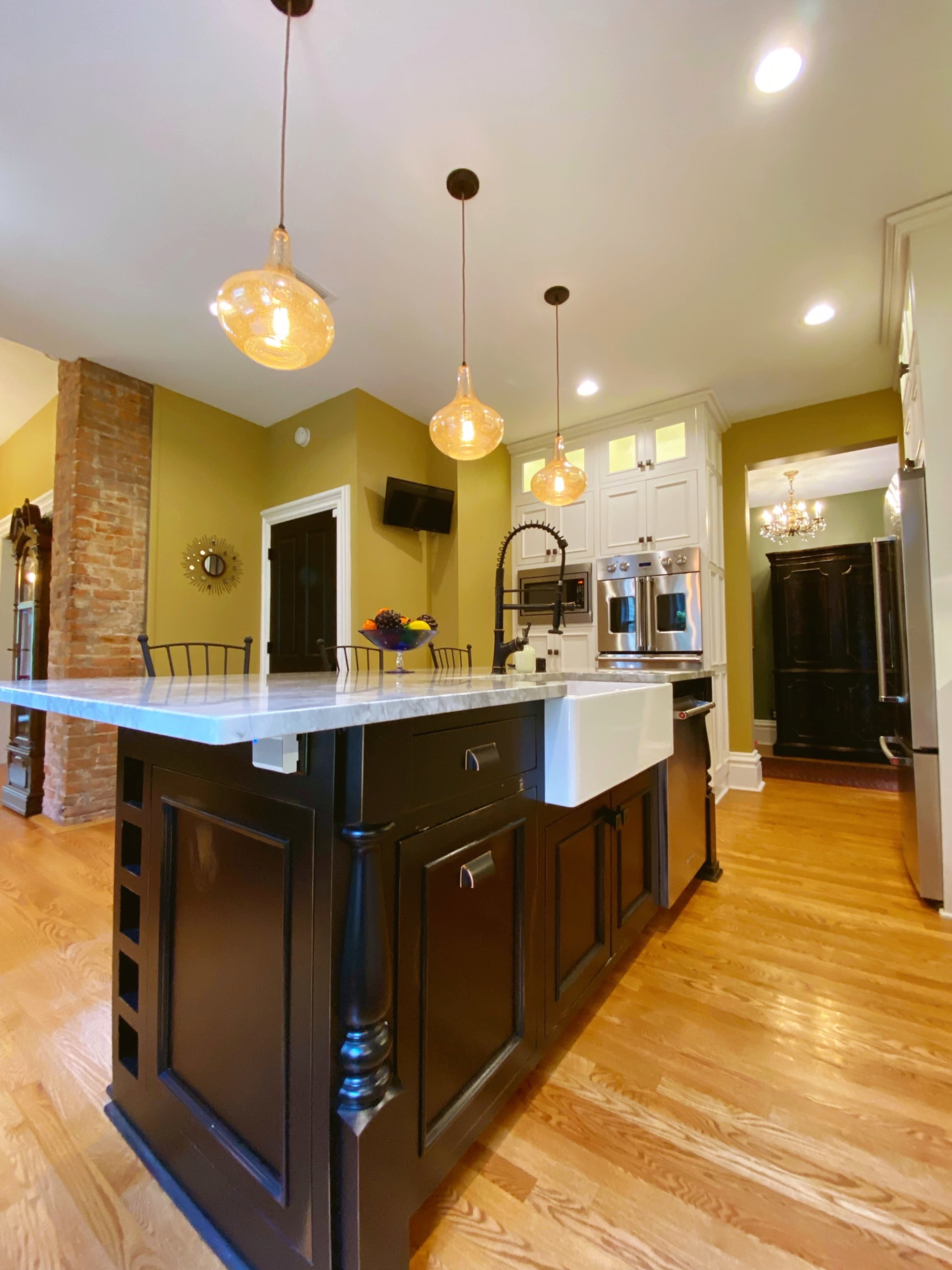 The kitchen features a central island with a white countertop, black cabinetry, and three pendant lights hanging above.